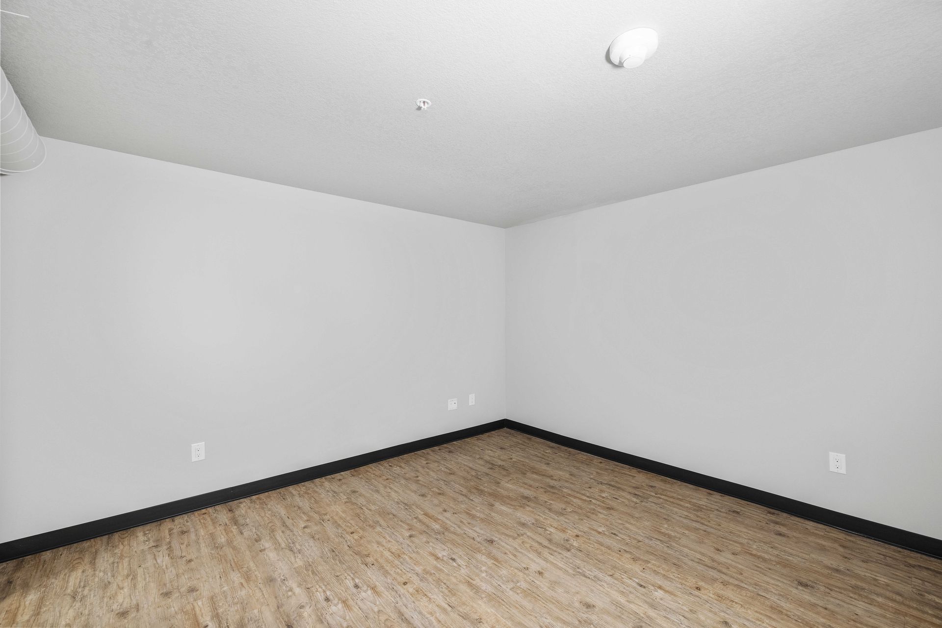 an empty room with hardwood floors and a window .