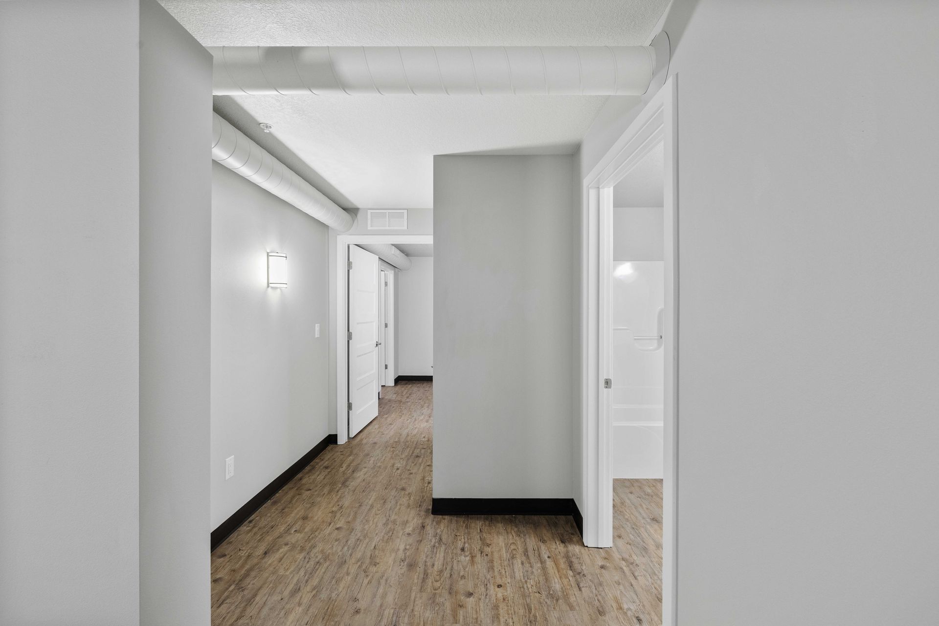a hallway in a house with hardwood floors and white walls .