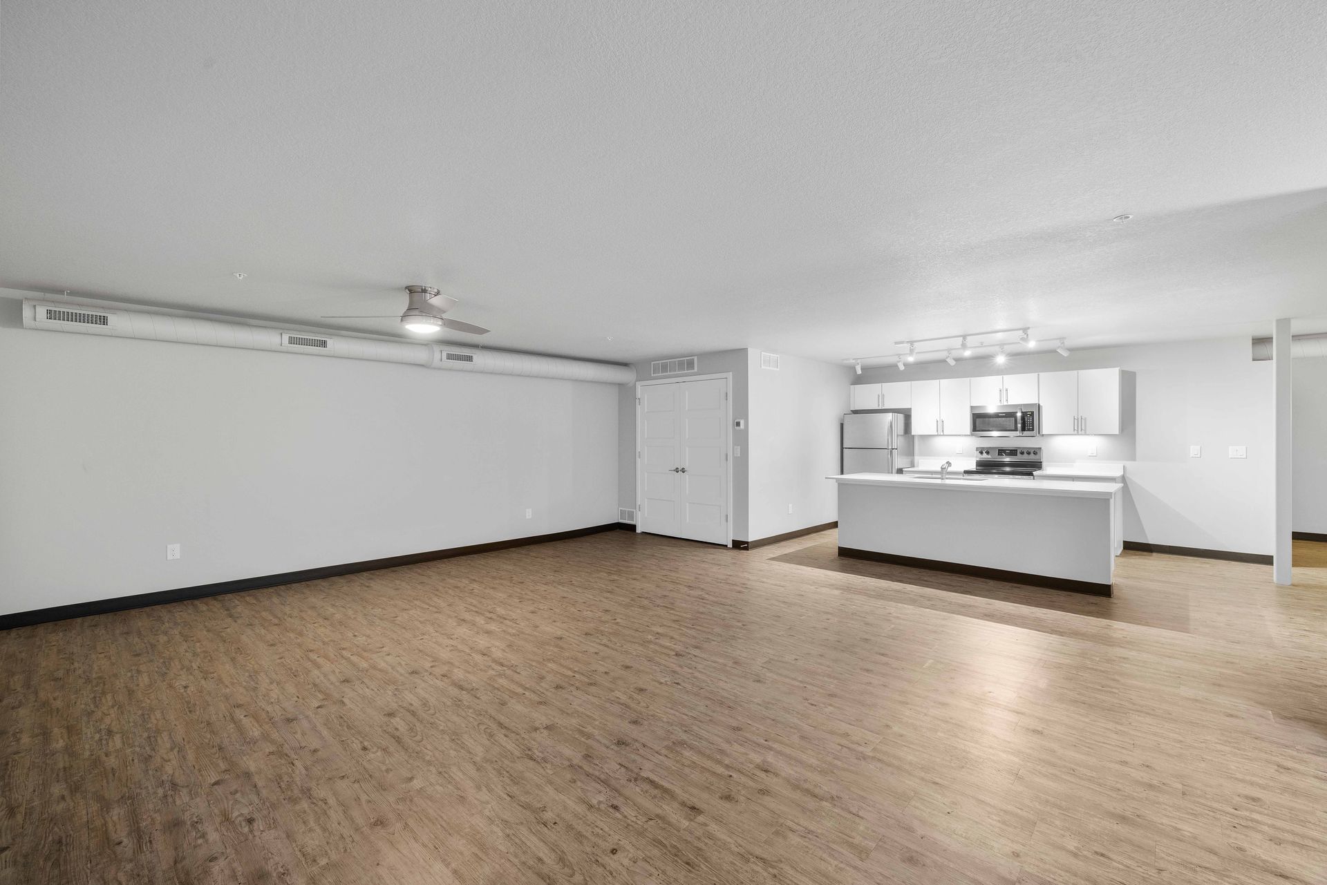 a large empty room with hardwood floors and a ceiling fan .
