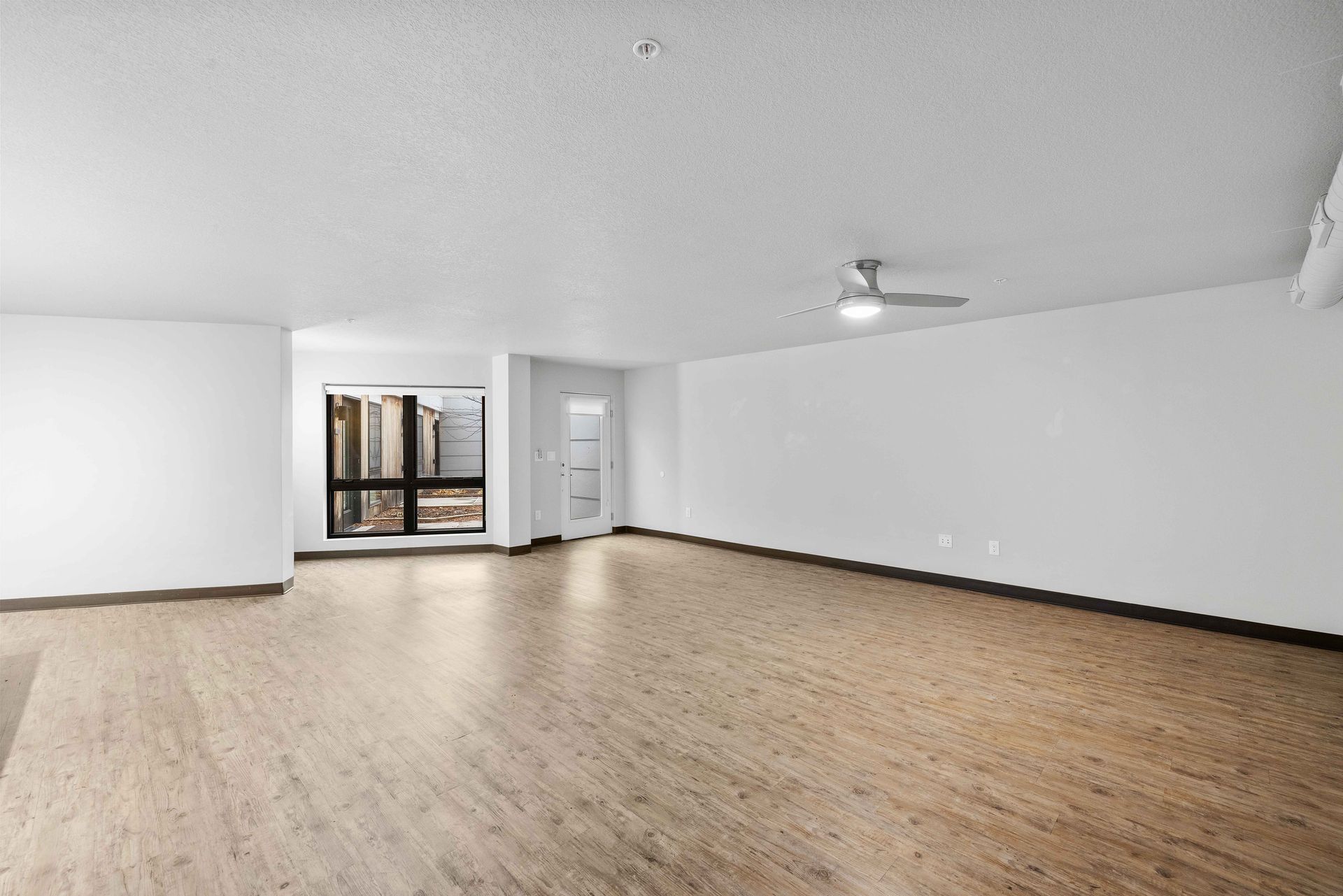 an empty living room with hardwood floors and white walls .