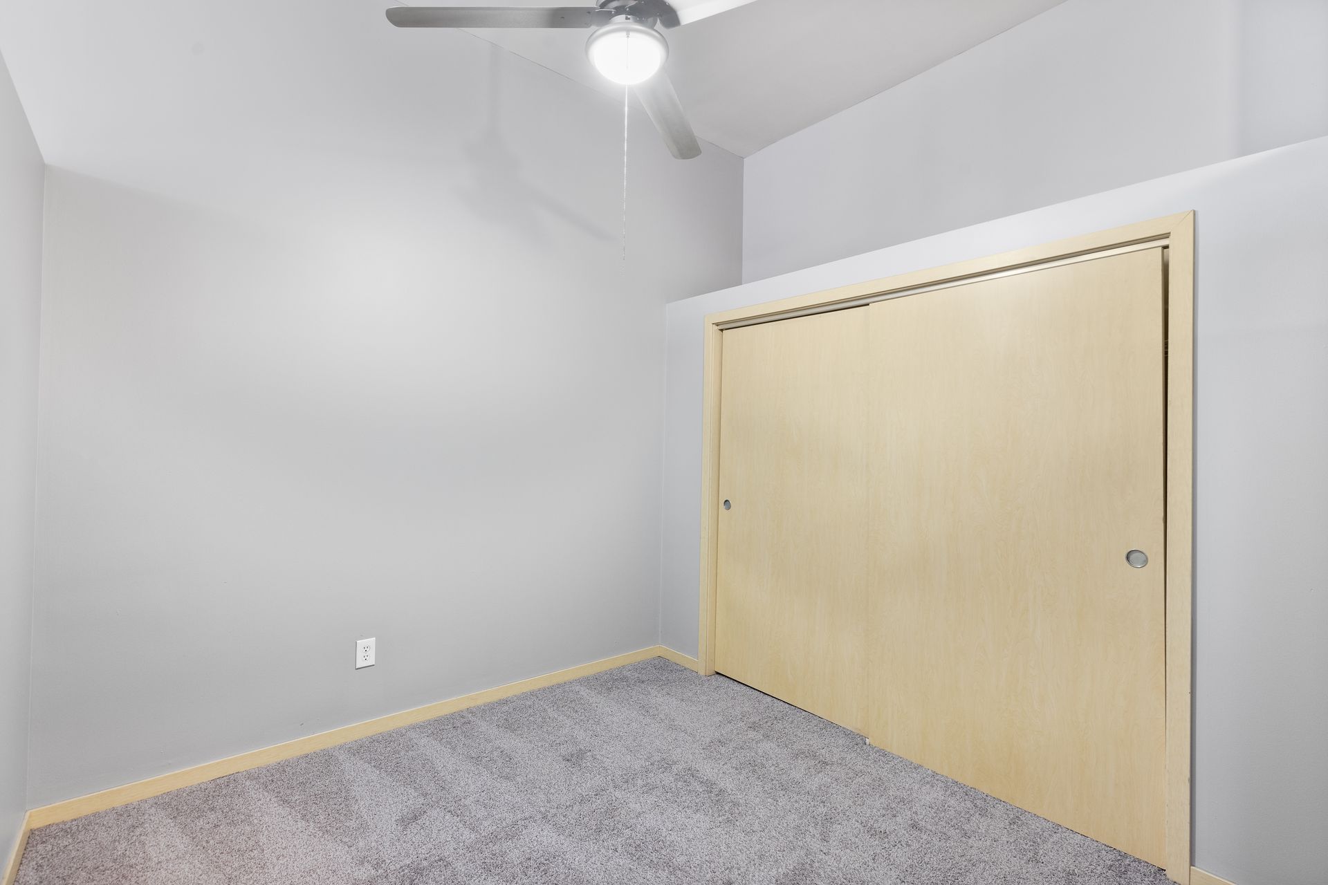 an empty bedroom with a ceiling fan and a closet .