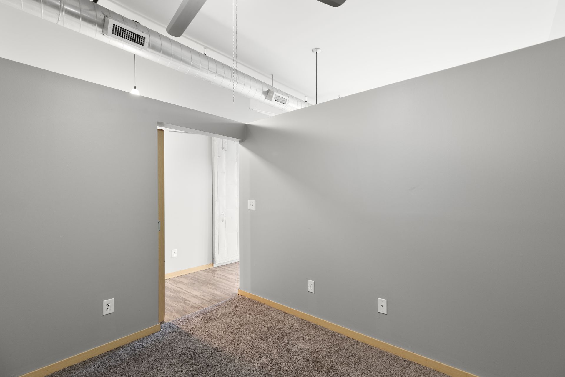 an empty room with gray walls and a ceiling fan .