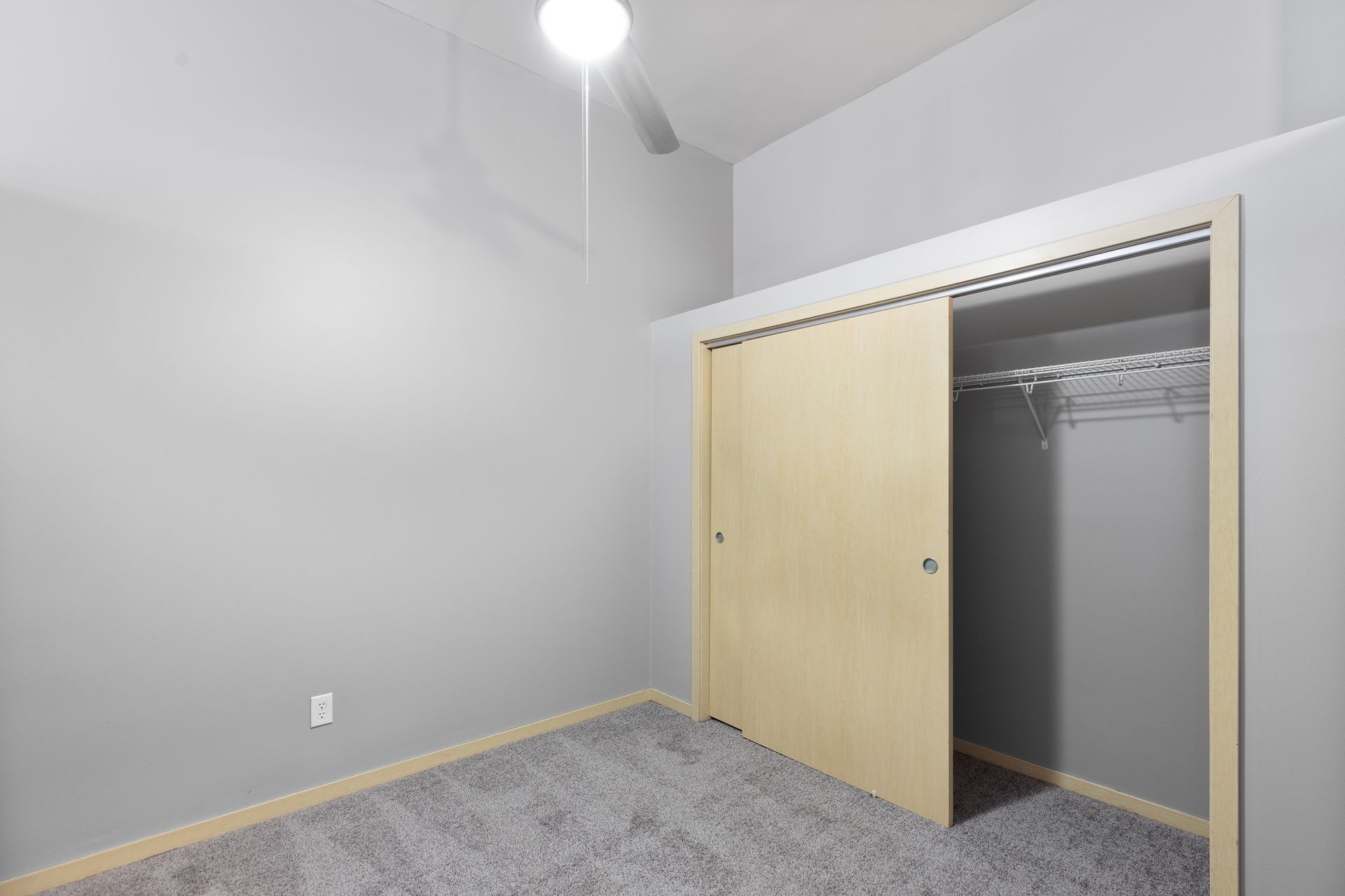 an empty bedroom with a closet and a ceiling fan .