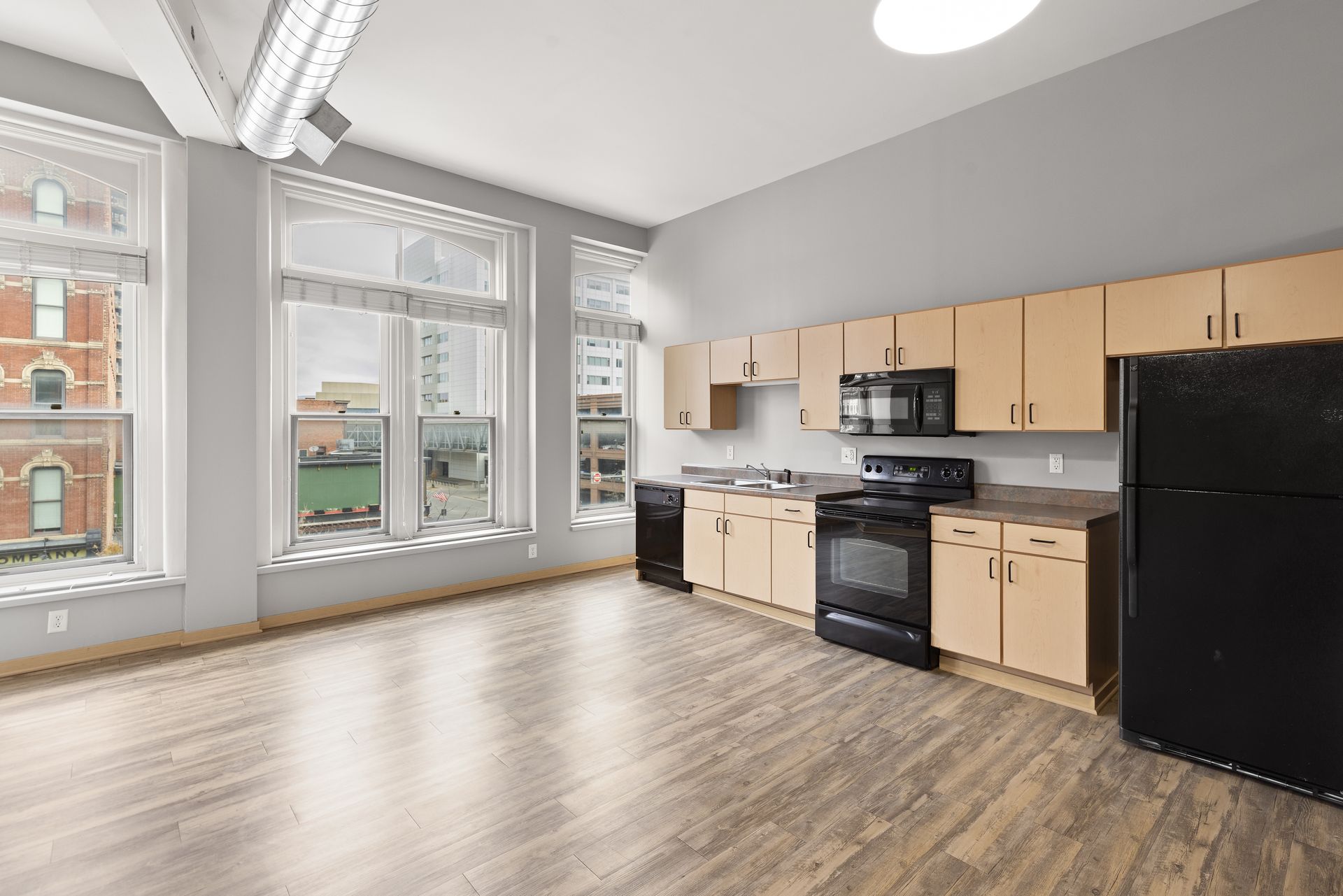 an empty kitchen with wooden cabinets and a black refrigerator .