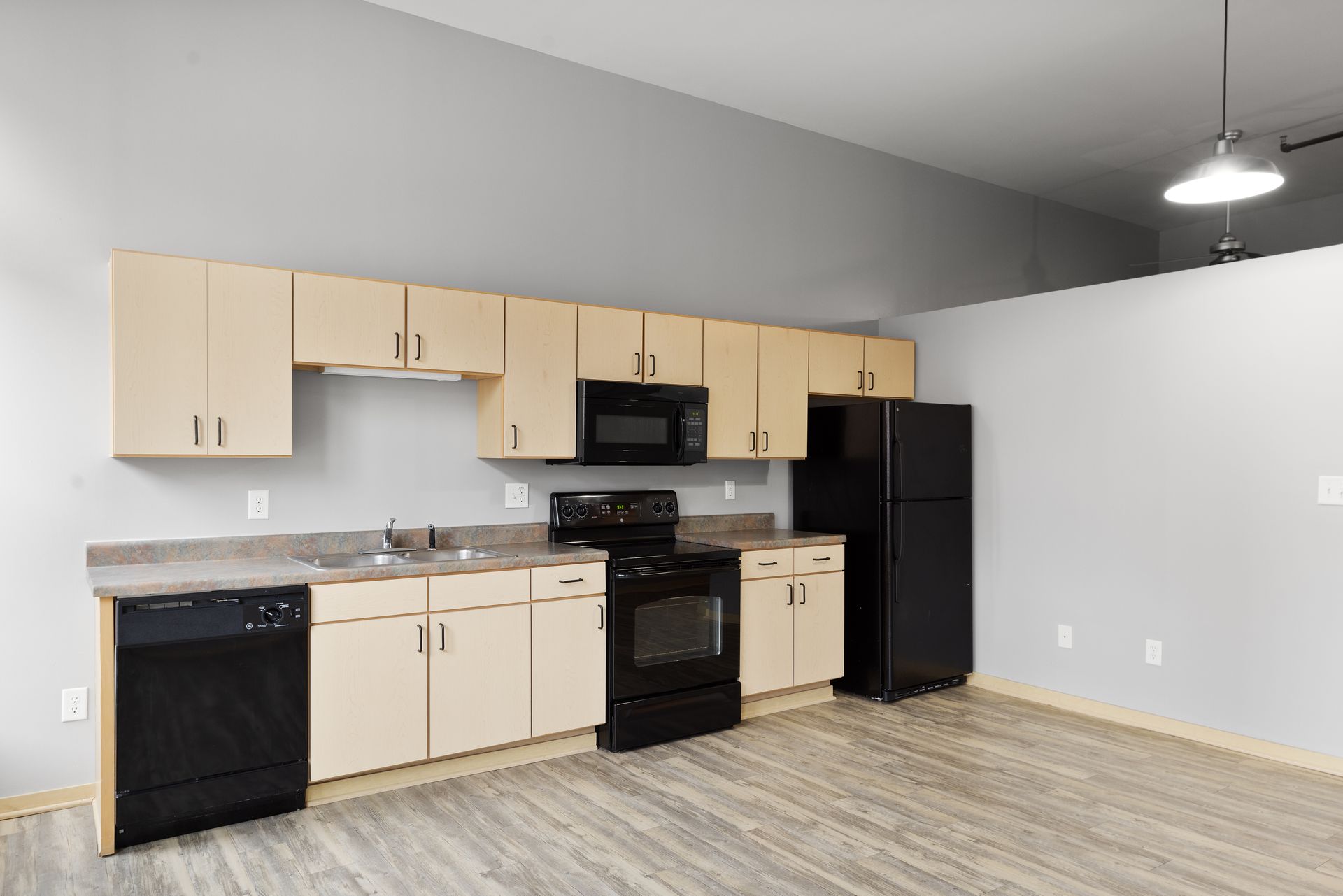 an empty kitchen with wooden cabinets , a black refrigerator , a black stove , and a black dishwasher .