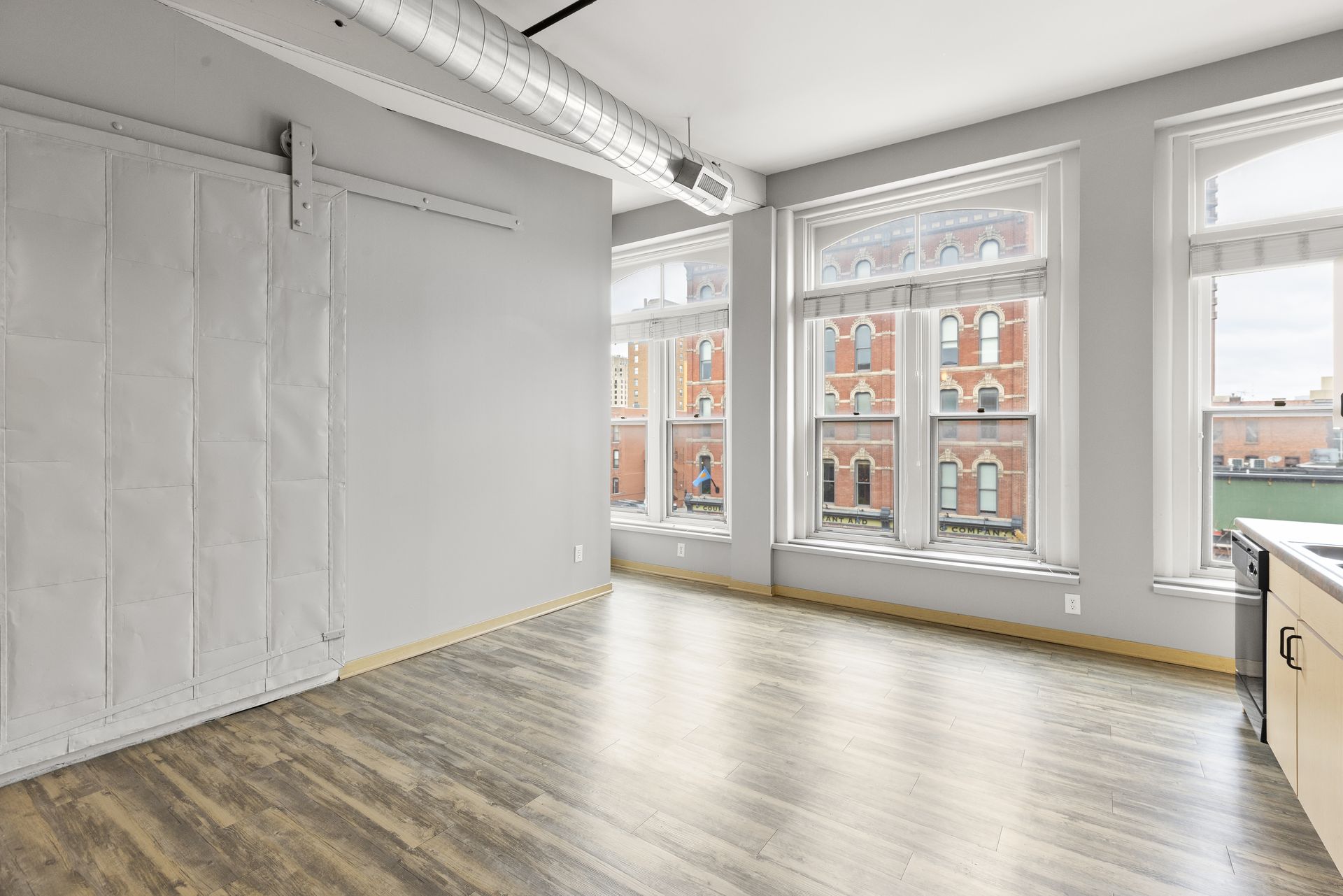 a large empty room with hardwood floors and lots of windows .