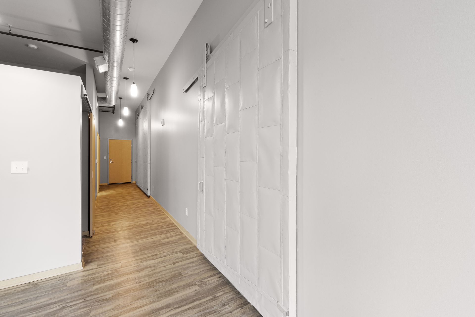 a long hallway with white walls and wooden floors in a building .