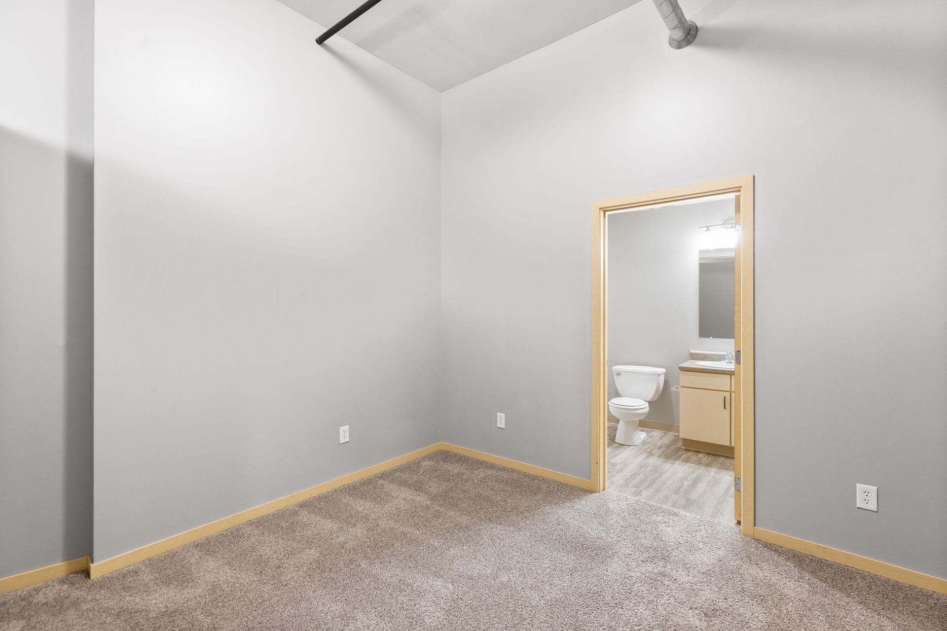 an empty bedroom with a toilet , sink and mirror .