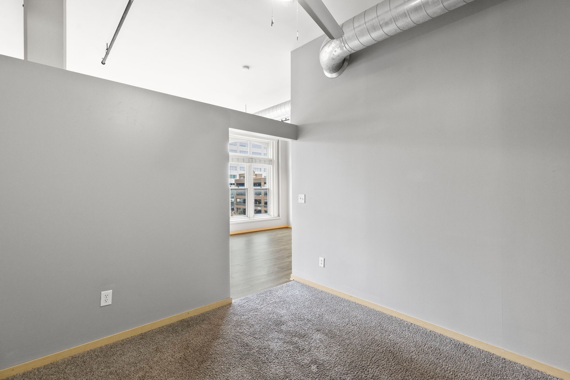 an empty room with a carpeted floor and gray walls .