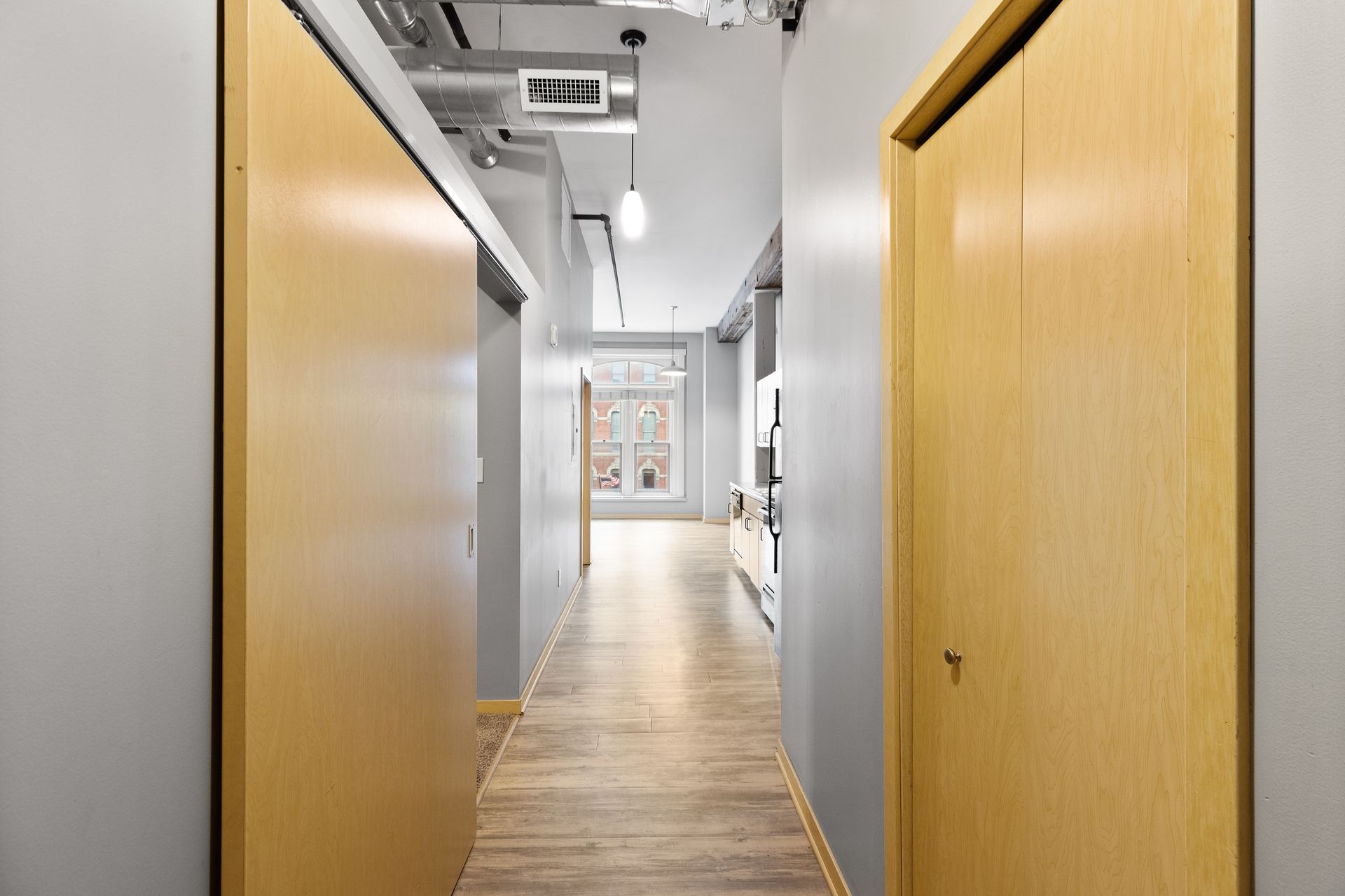 a long hallway with wooden floors and sliding doors leading to a kitchen .