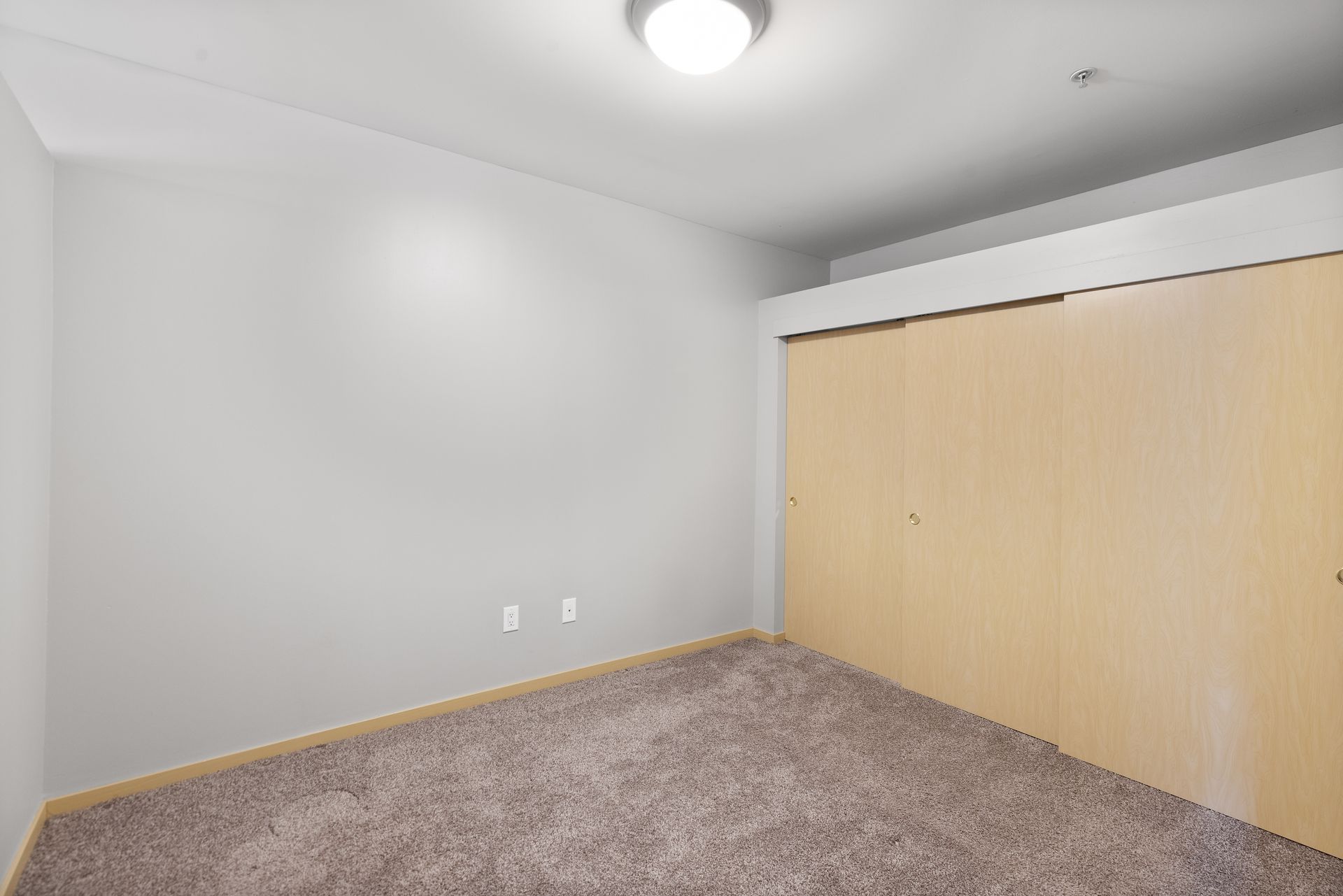 an empty bedroom with a closet and a light on the ceiling .