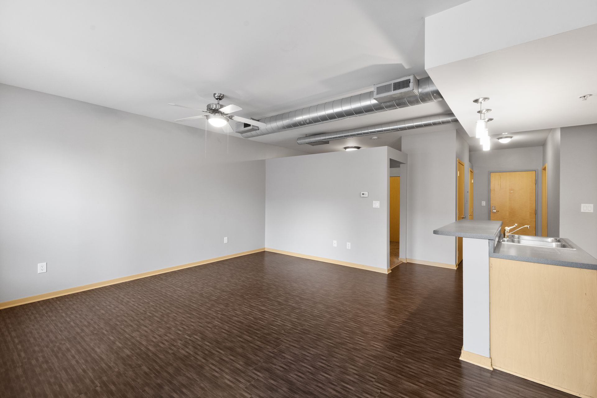 an empty living room with a wooden floor and white walls .