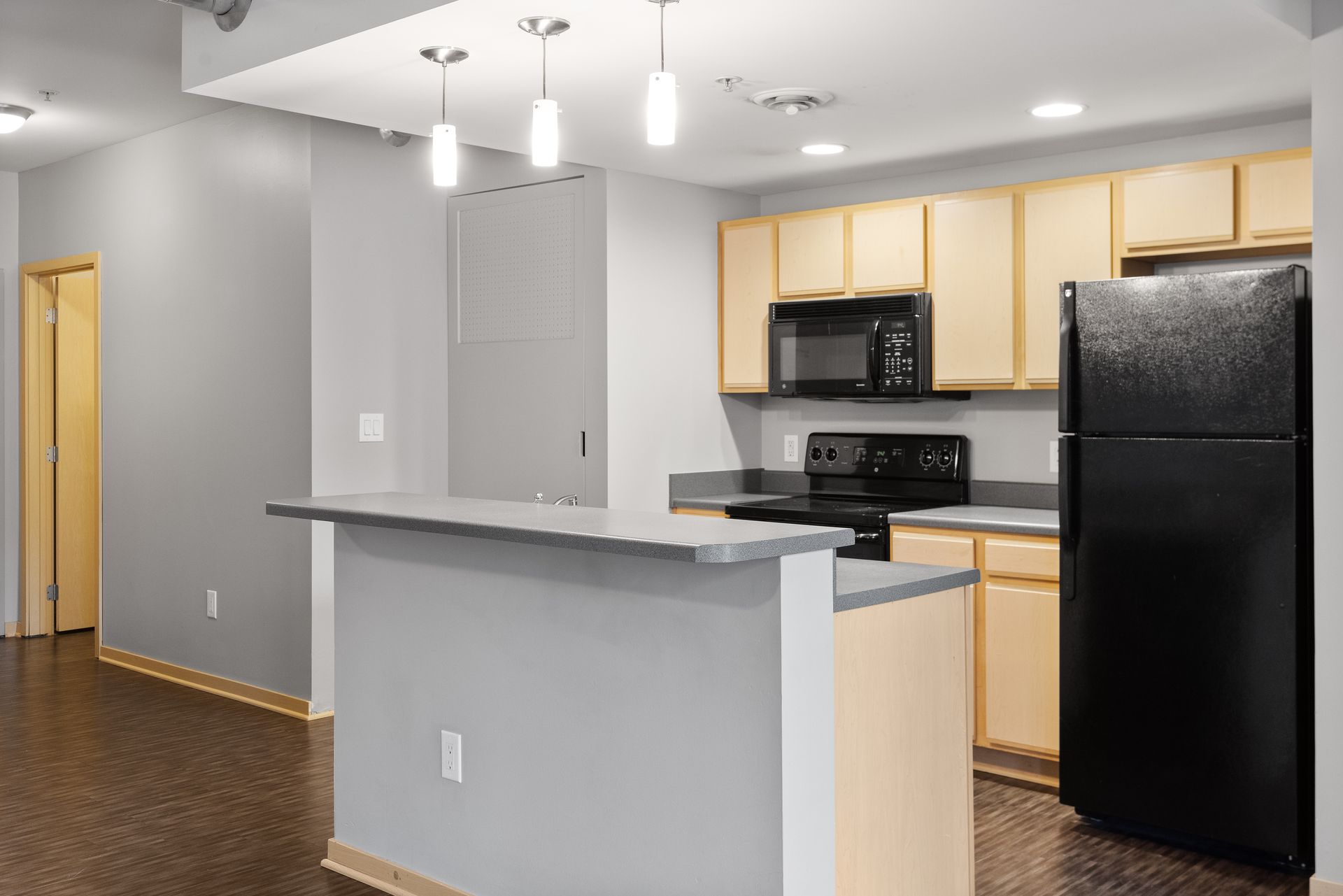 a kitchen with a black refrigerator , stove , microwave and sink .