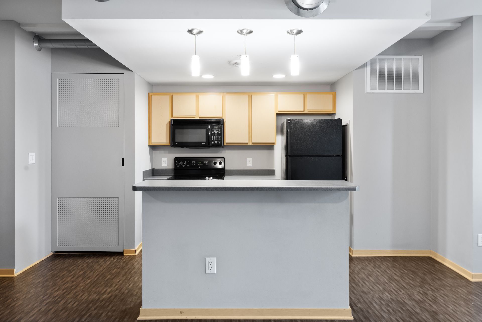 an empty kitchen with a stove , refrigerator , microwave , and sink .