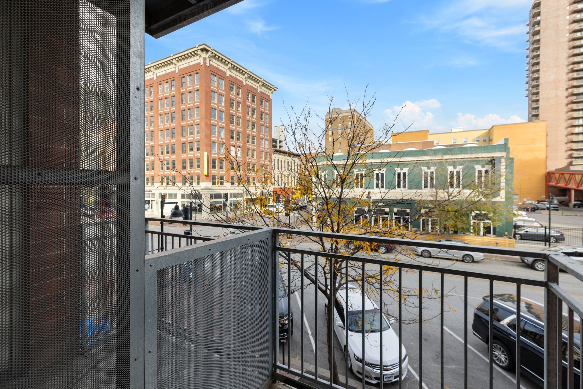 a balcony overlooking a city street with cars parked on the side of the road .