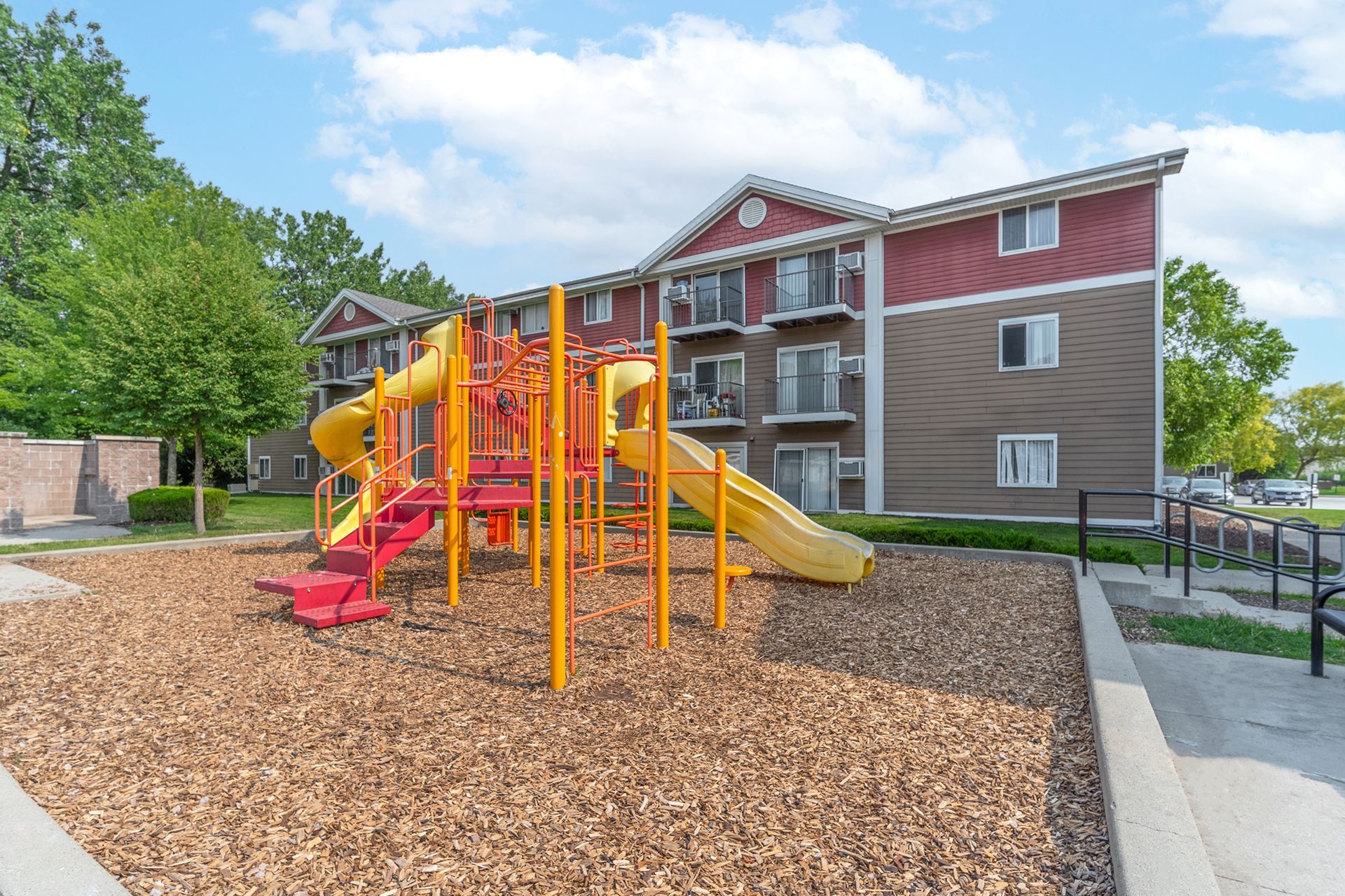 a playground with a slide and stairs in front of a building .