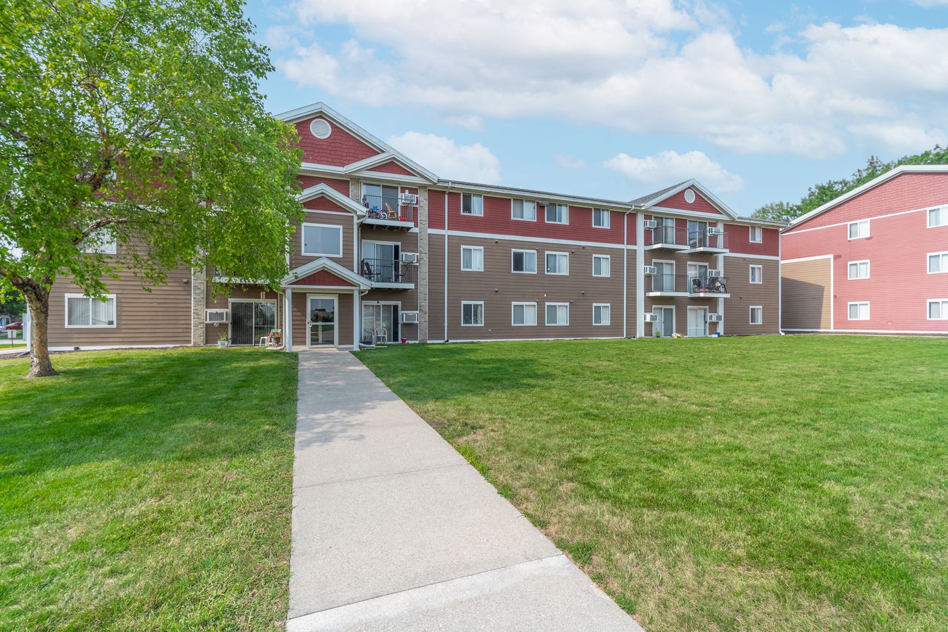 there is a walkway leading to a large apartment building .