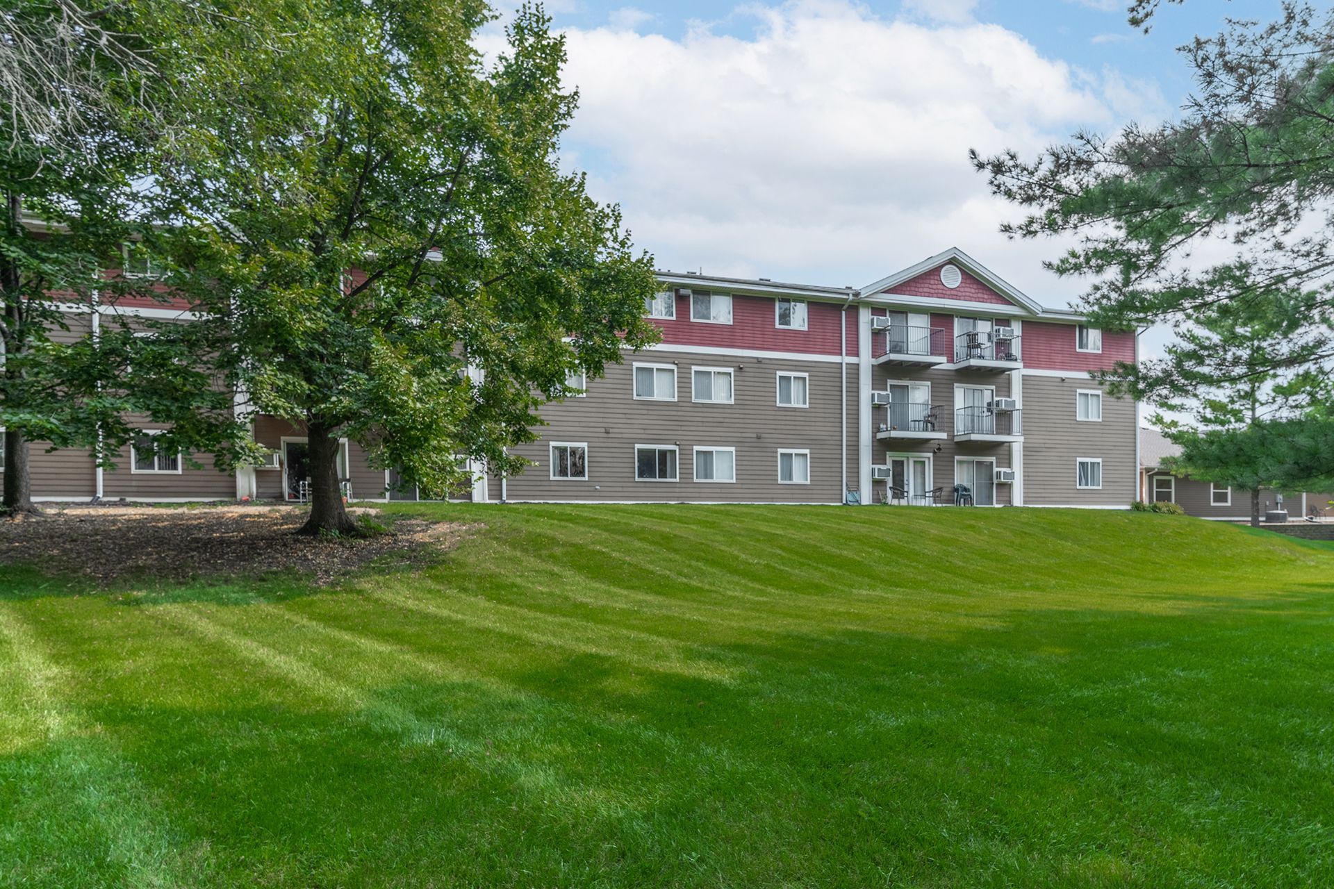 a large apartment building with a lush green lawn in front of it