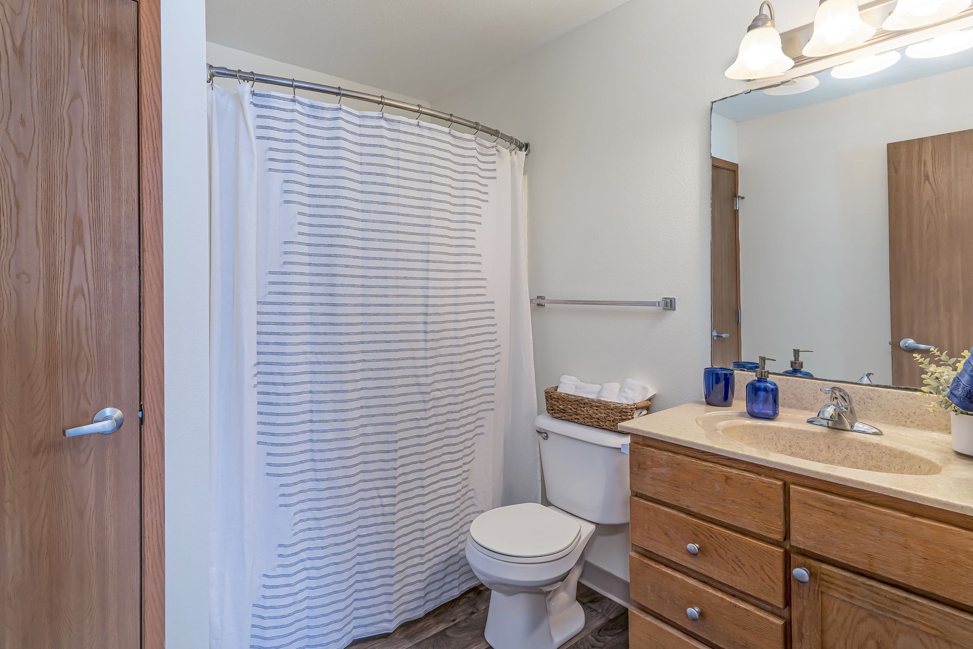 a bathroom with a toilet , sink , mirror and shower curtain .