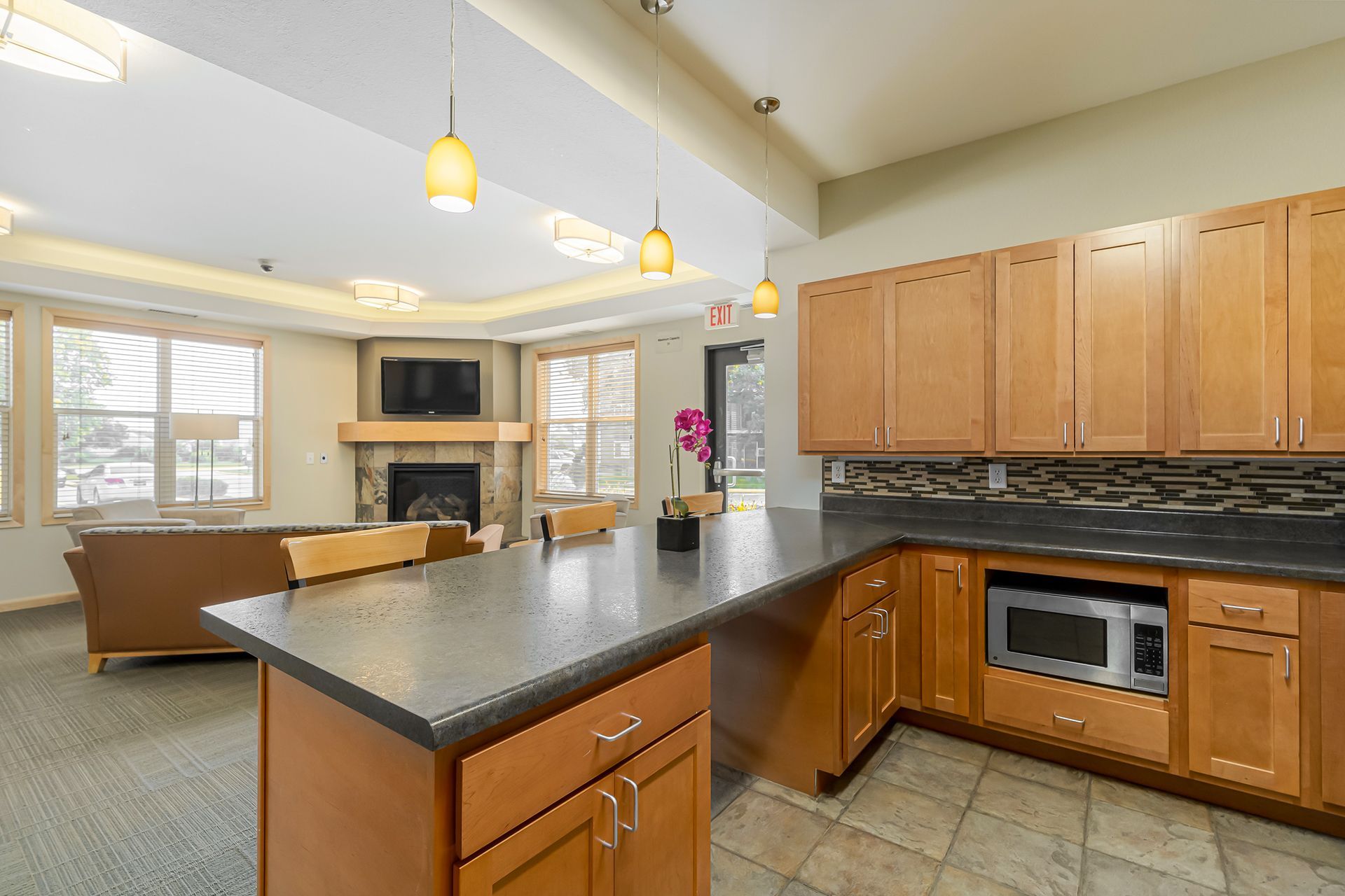 a kitchen with wooden cabinets , granite counter tops , a microwave and a fireplace .