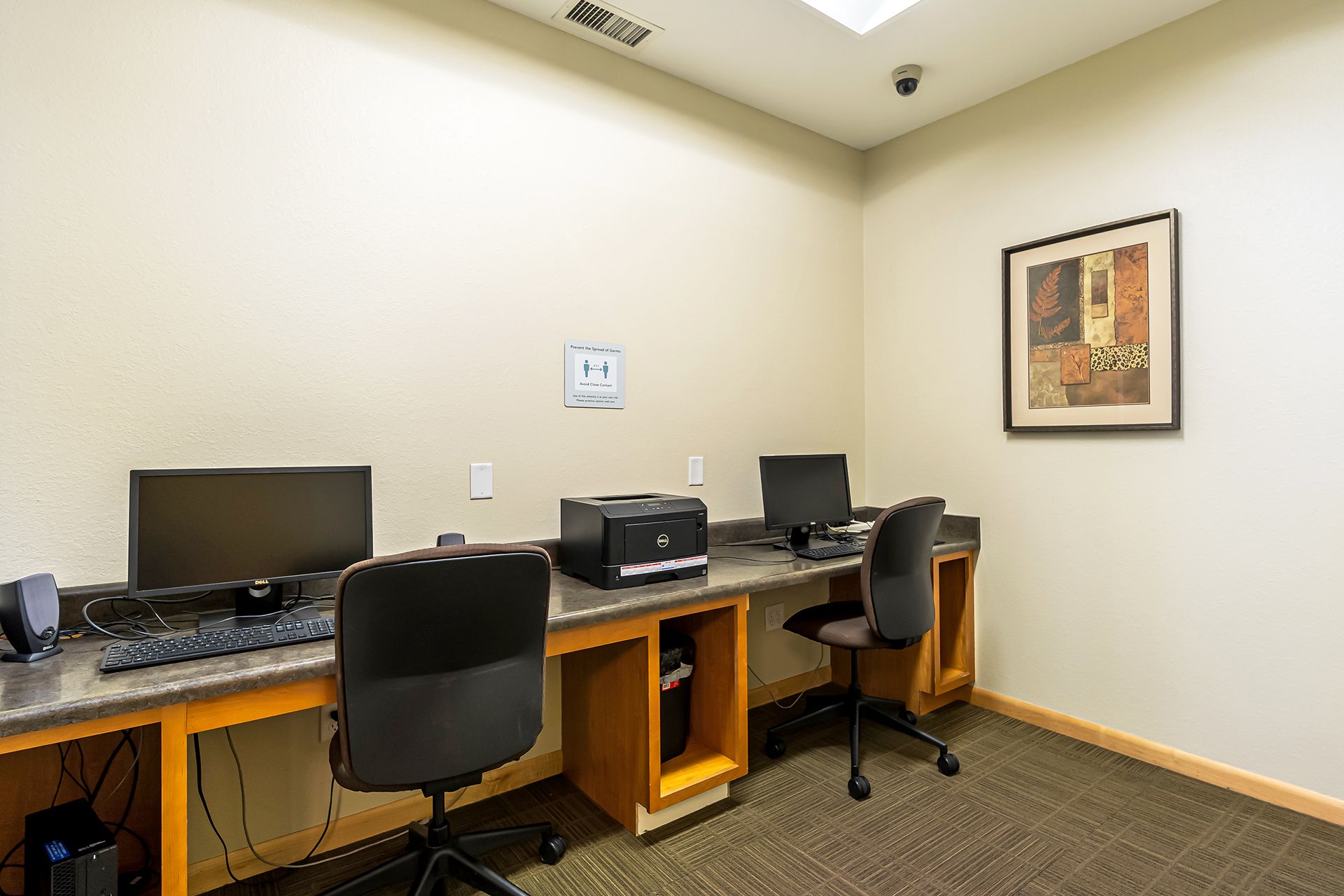 a room with two desks and two chairs filled with computers and printers .