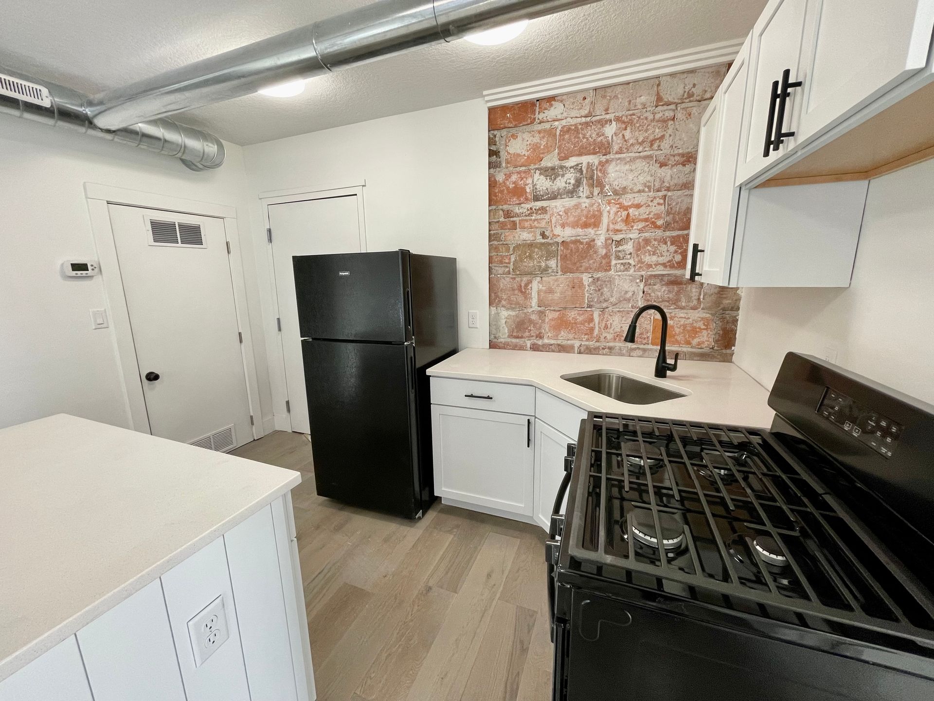 a kitchen with a black refrigerator , black stove , and white cabinets .