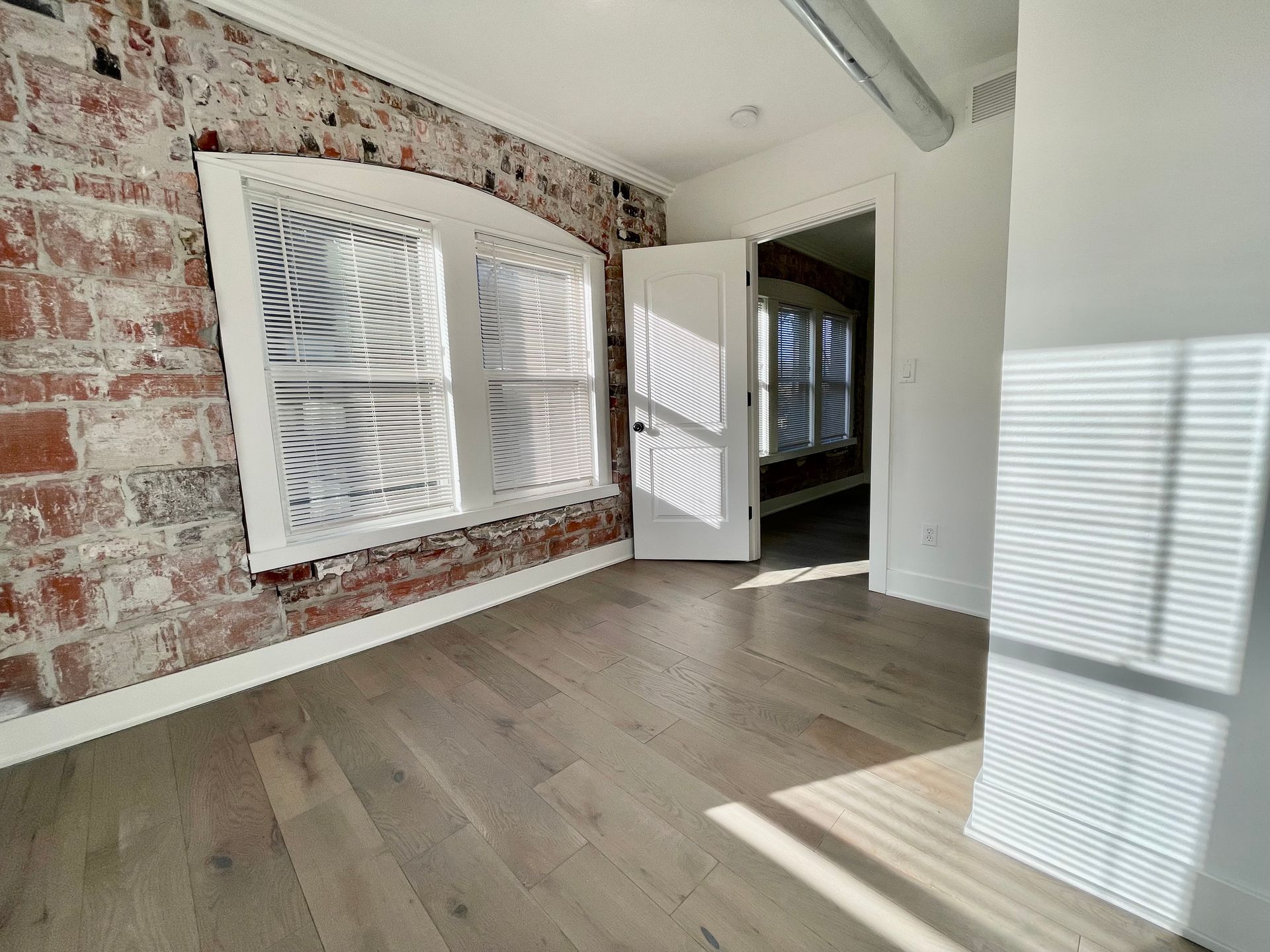 an empty room with hardwood floors and a brick wall .