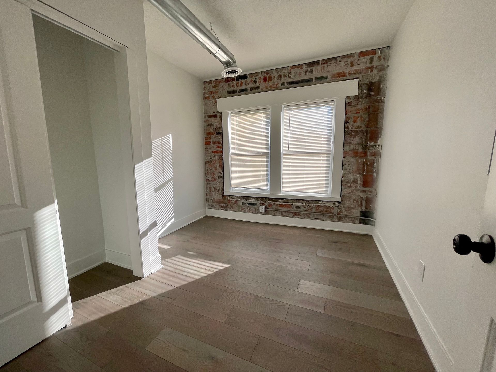 an empty room with a brick wall and two windows .