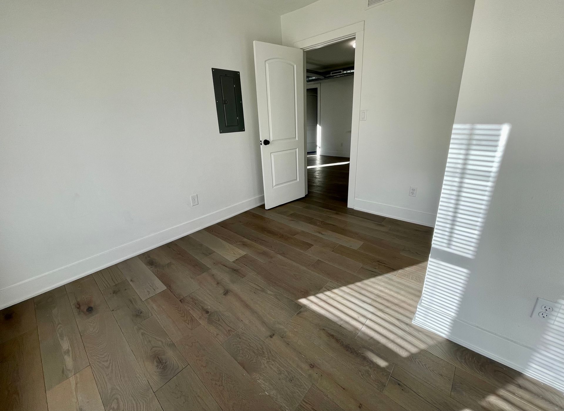 an empty room with hardwood floors and white walls .