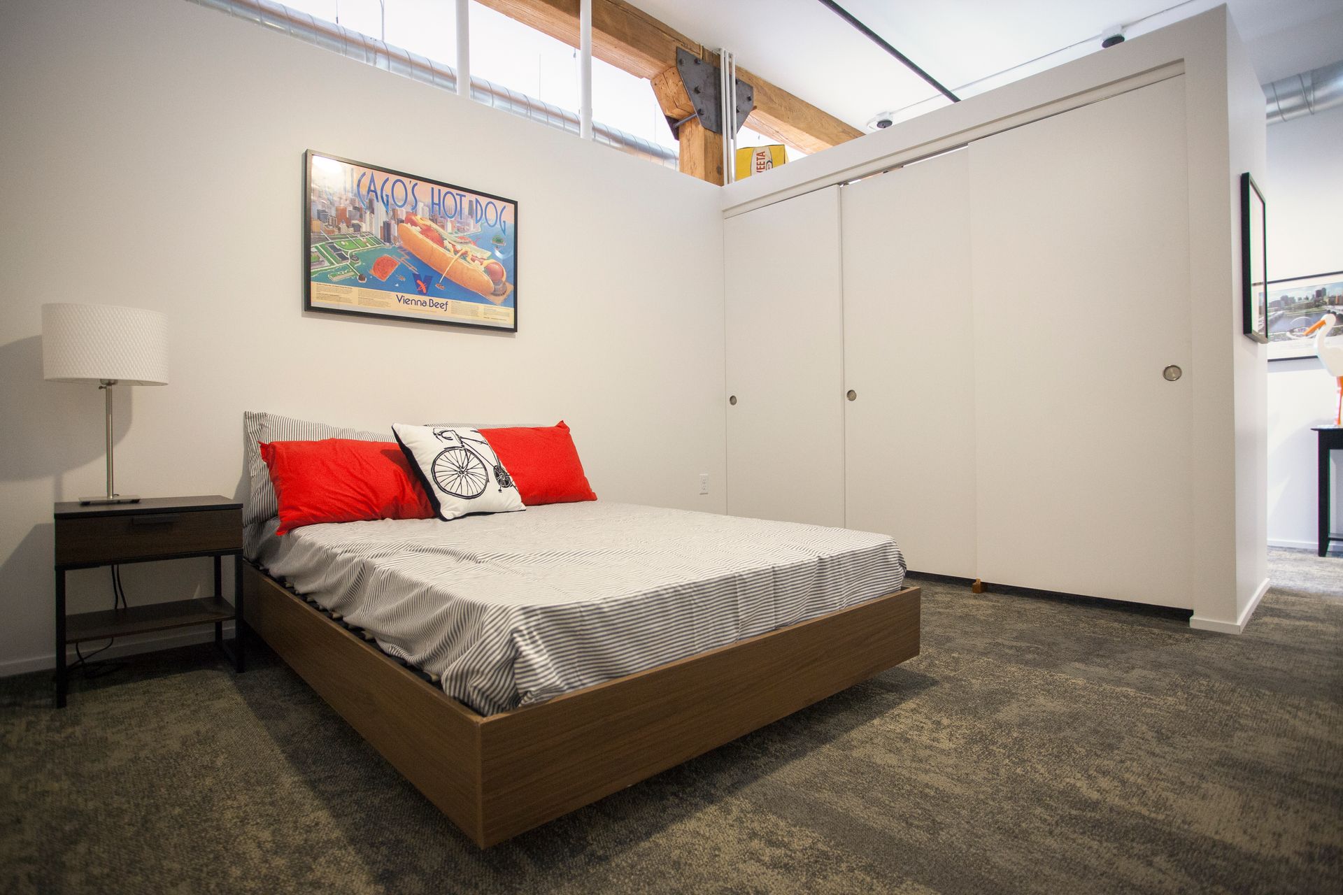 a bedroom with a bed , nightstand , lamp and a picture on the wall .