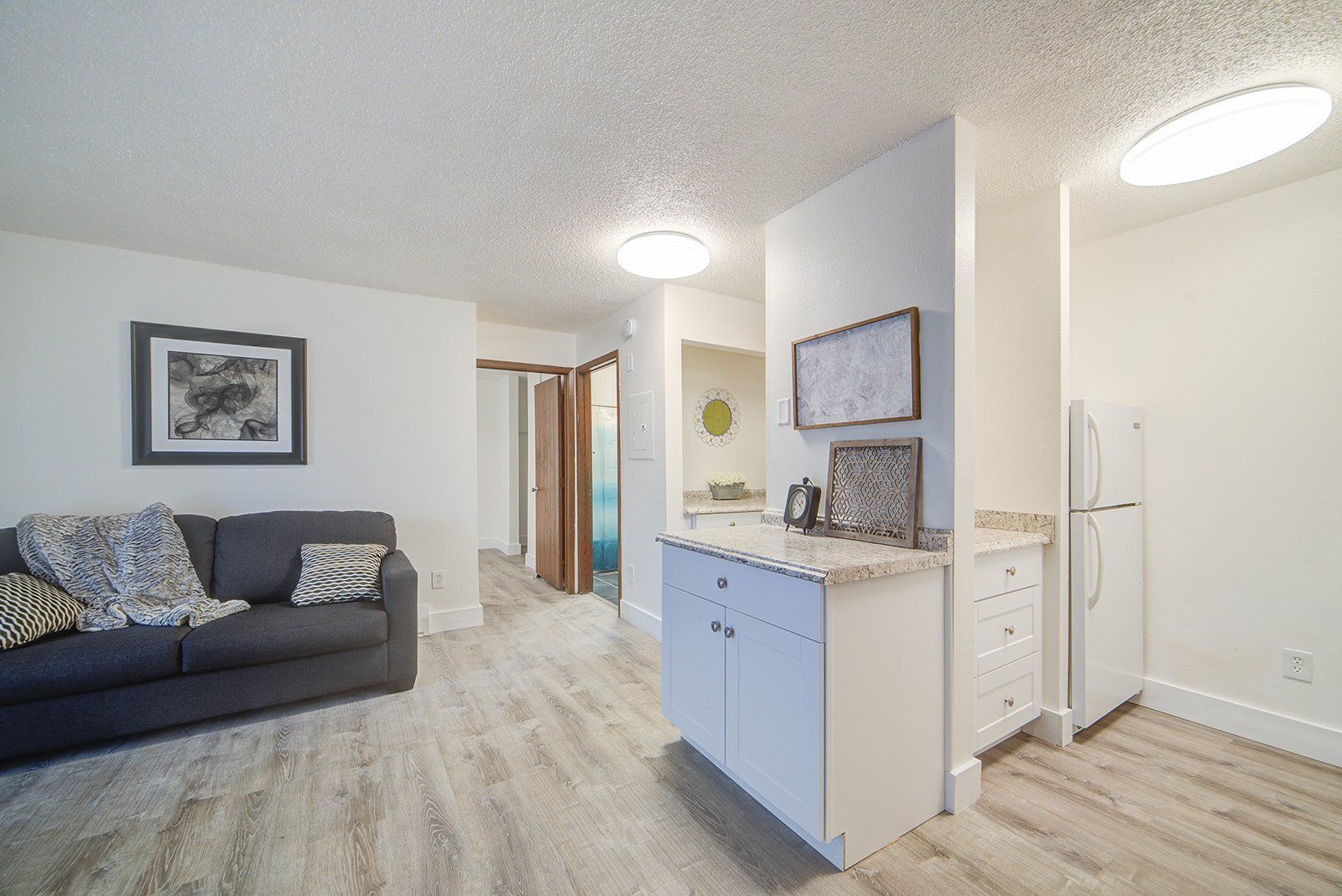 a living room with a couch , kitchen , and refrigerator .