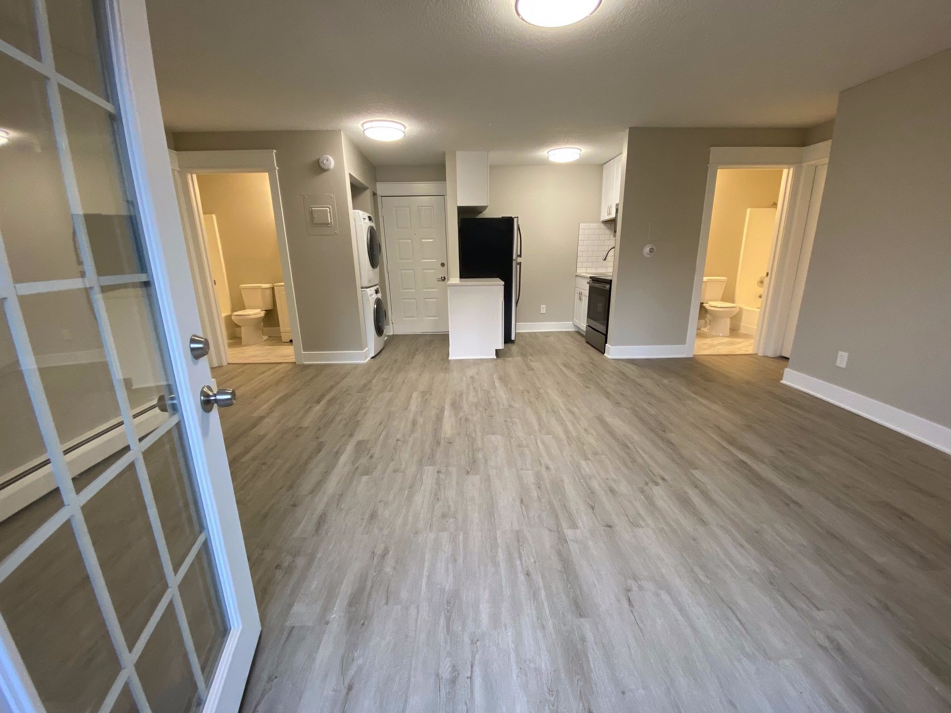 a living room with hardwood floors and a french door leading to a kitchen .