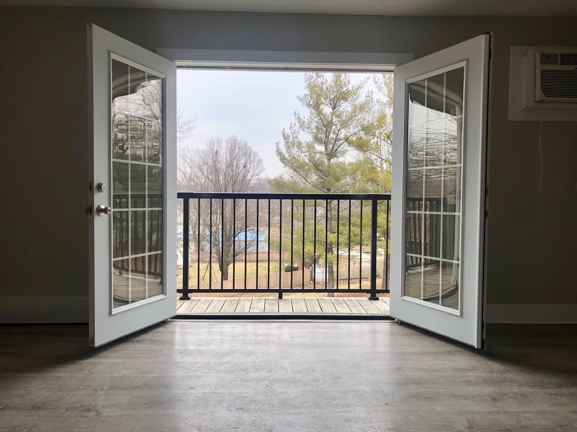 an empty room with a balcony and french doors open .