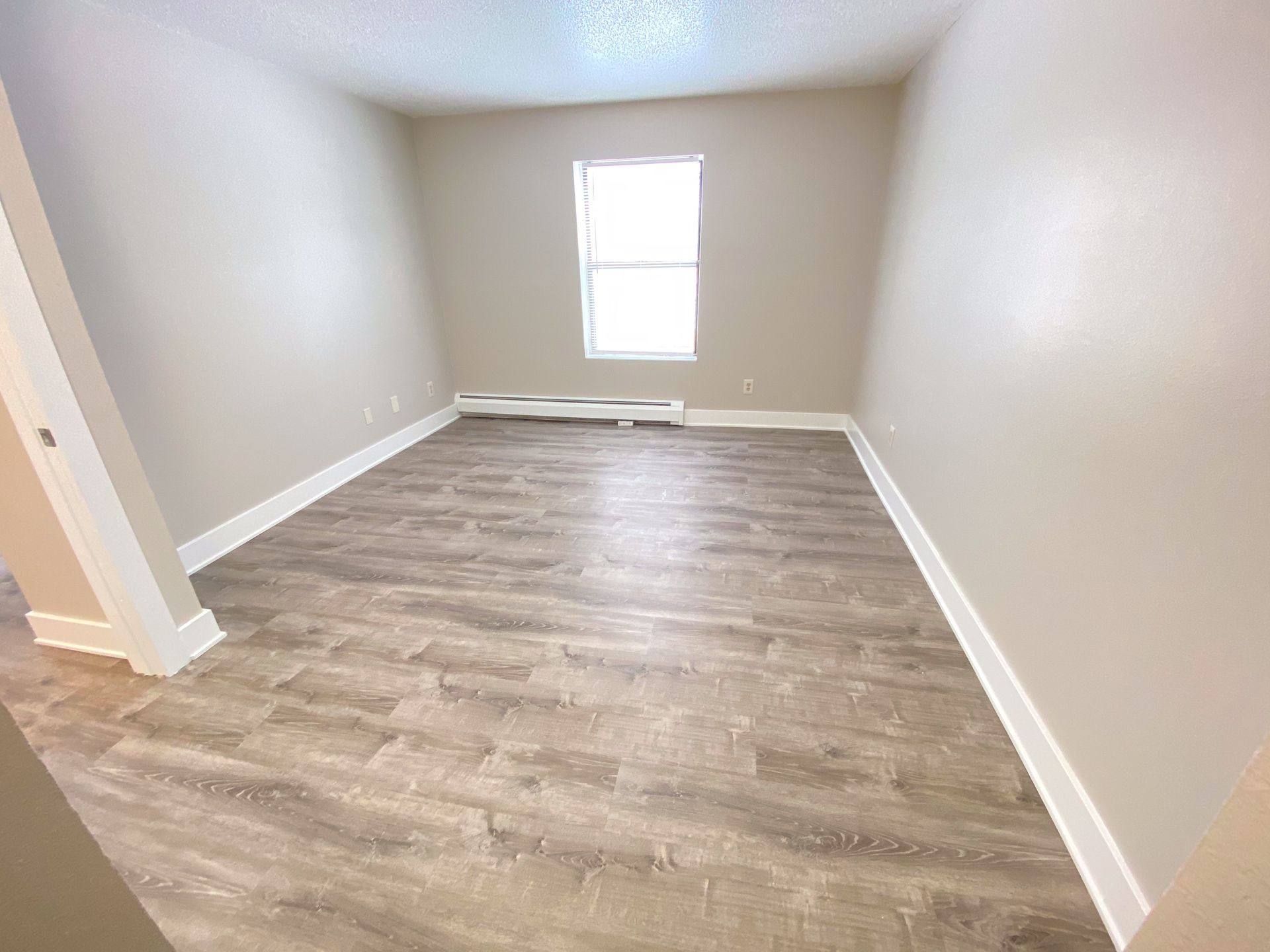 an empty room with hardwood floors and a window .