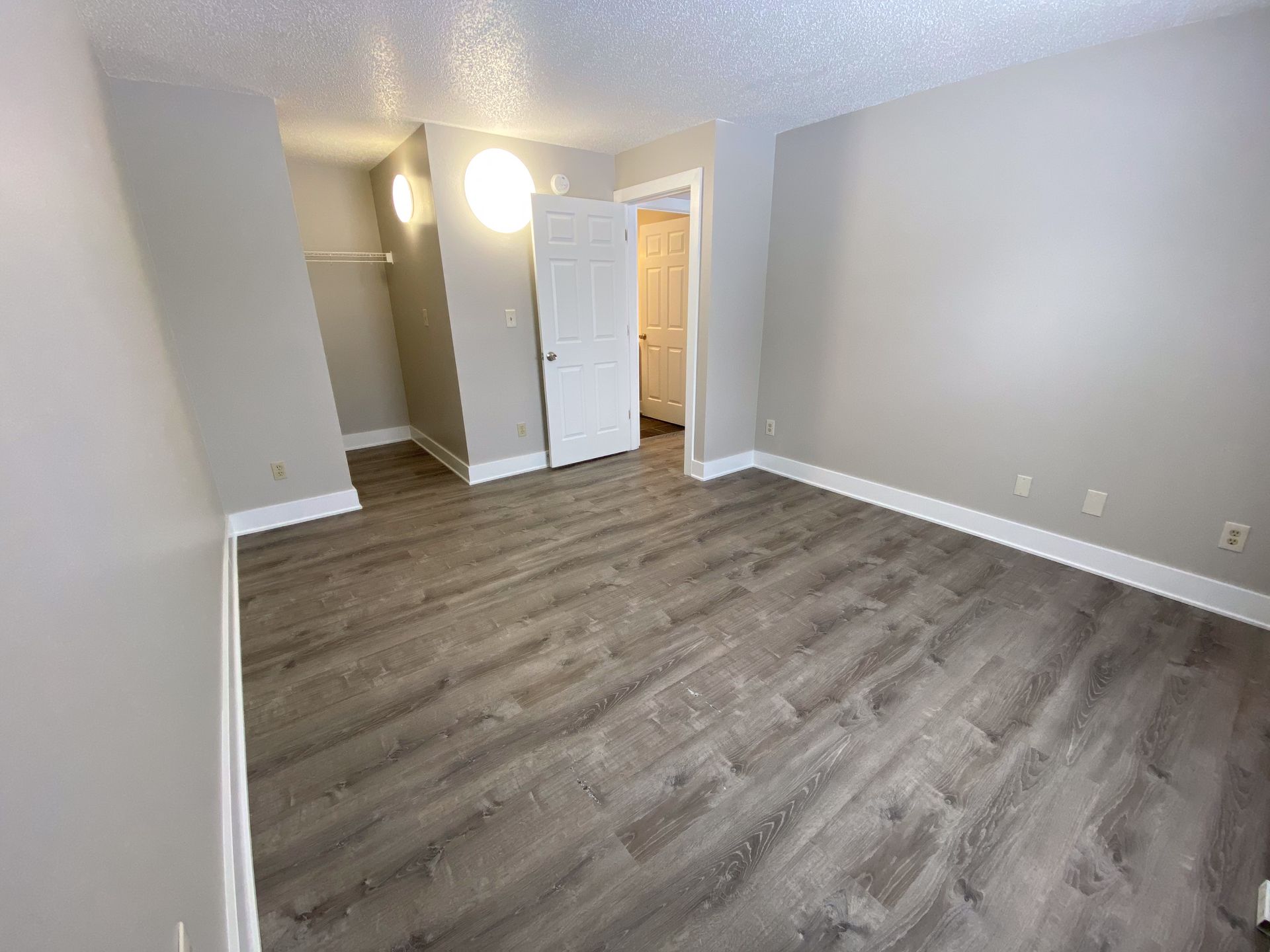 an empty room with hardwood floors and gray walls .