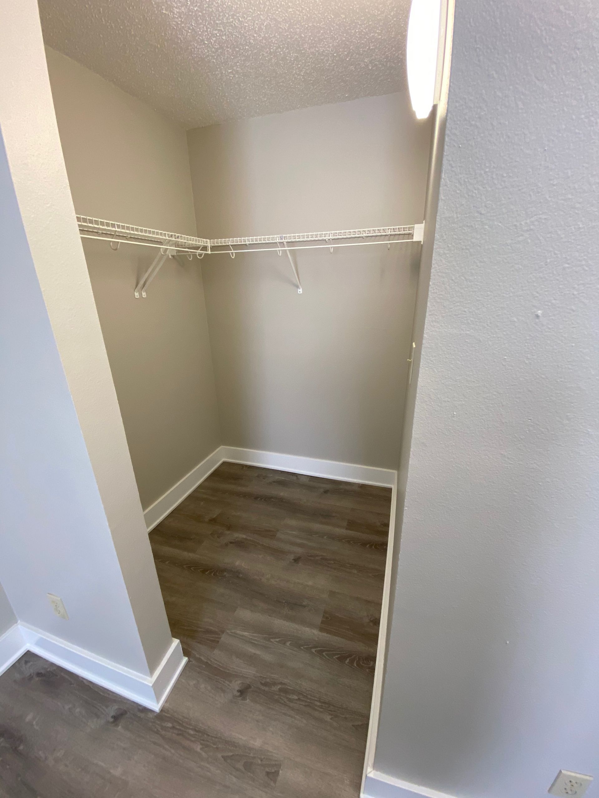 a walk in closet with hardwood floors and clothes racks .