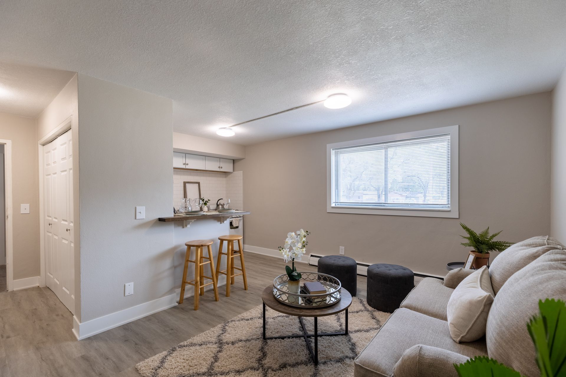 a living room with a couch , chair , coffee table and stools .