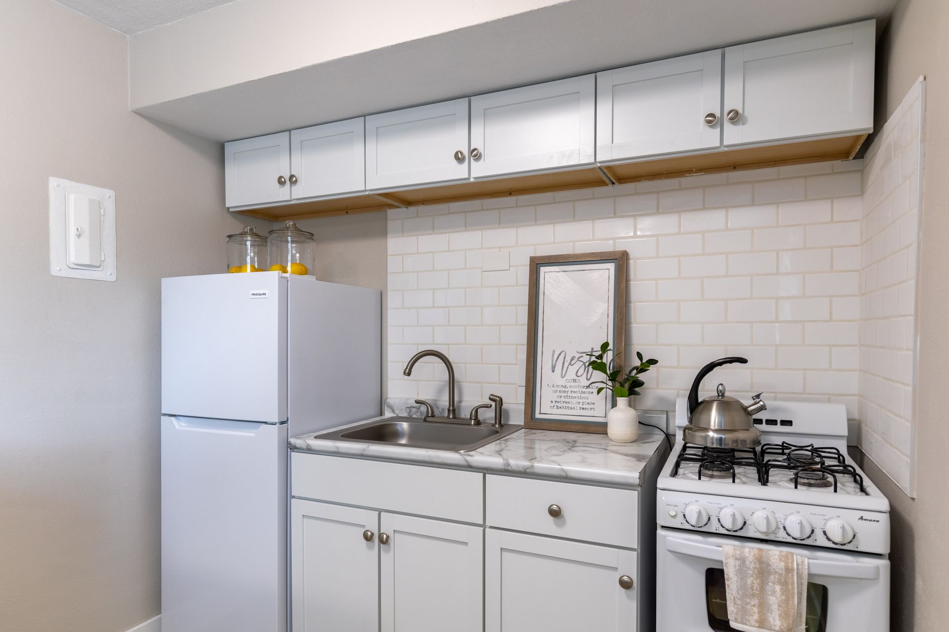 a small kitchen with a refrigerator , stove , sink and cabinets .