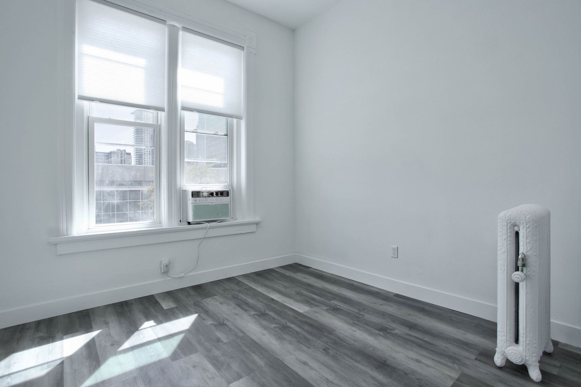 an empty room with a radiator and two windows .