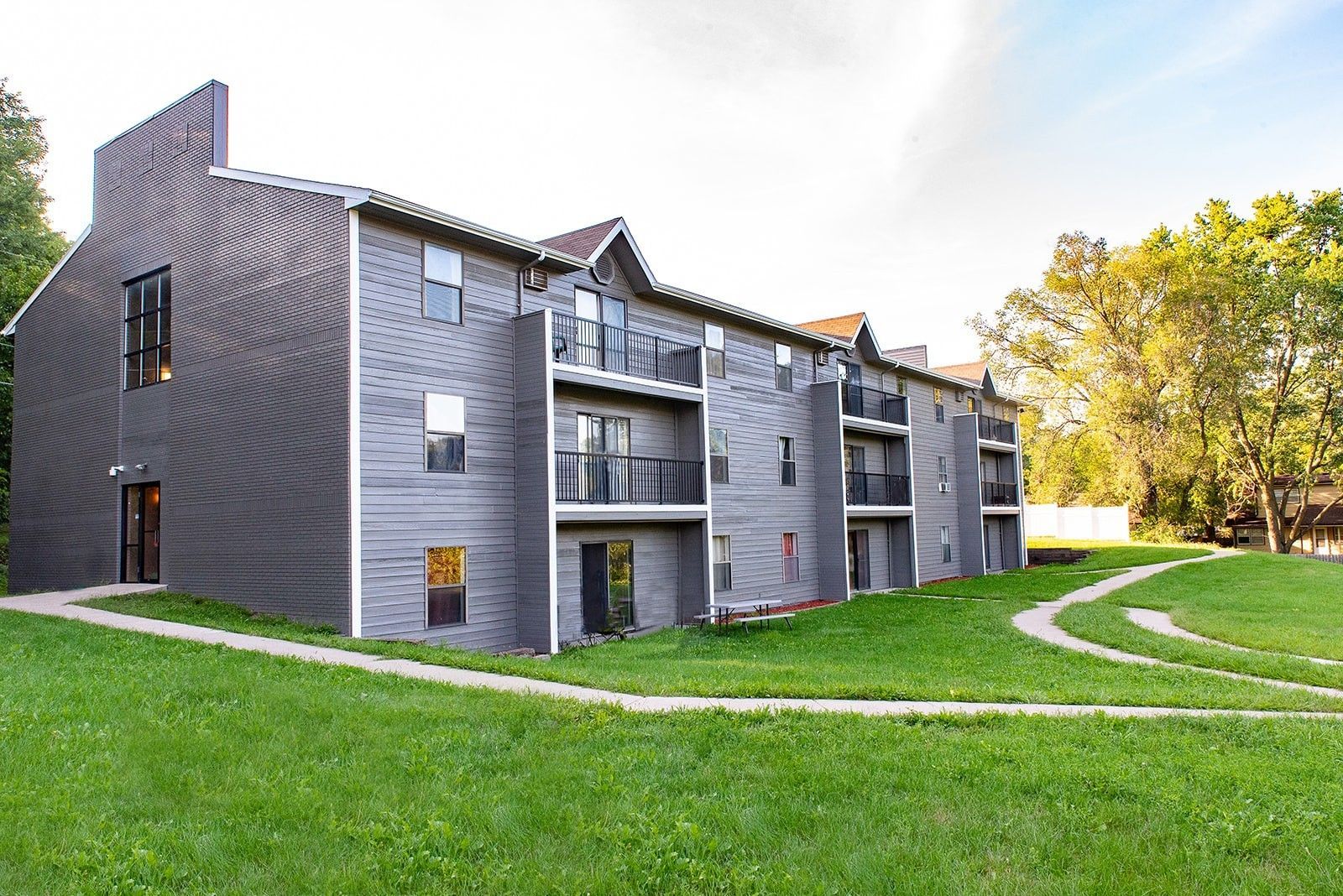 a large apartment building with a lush green lawn in front of it .