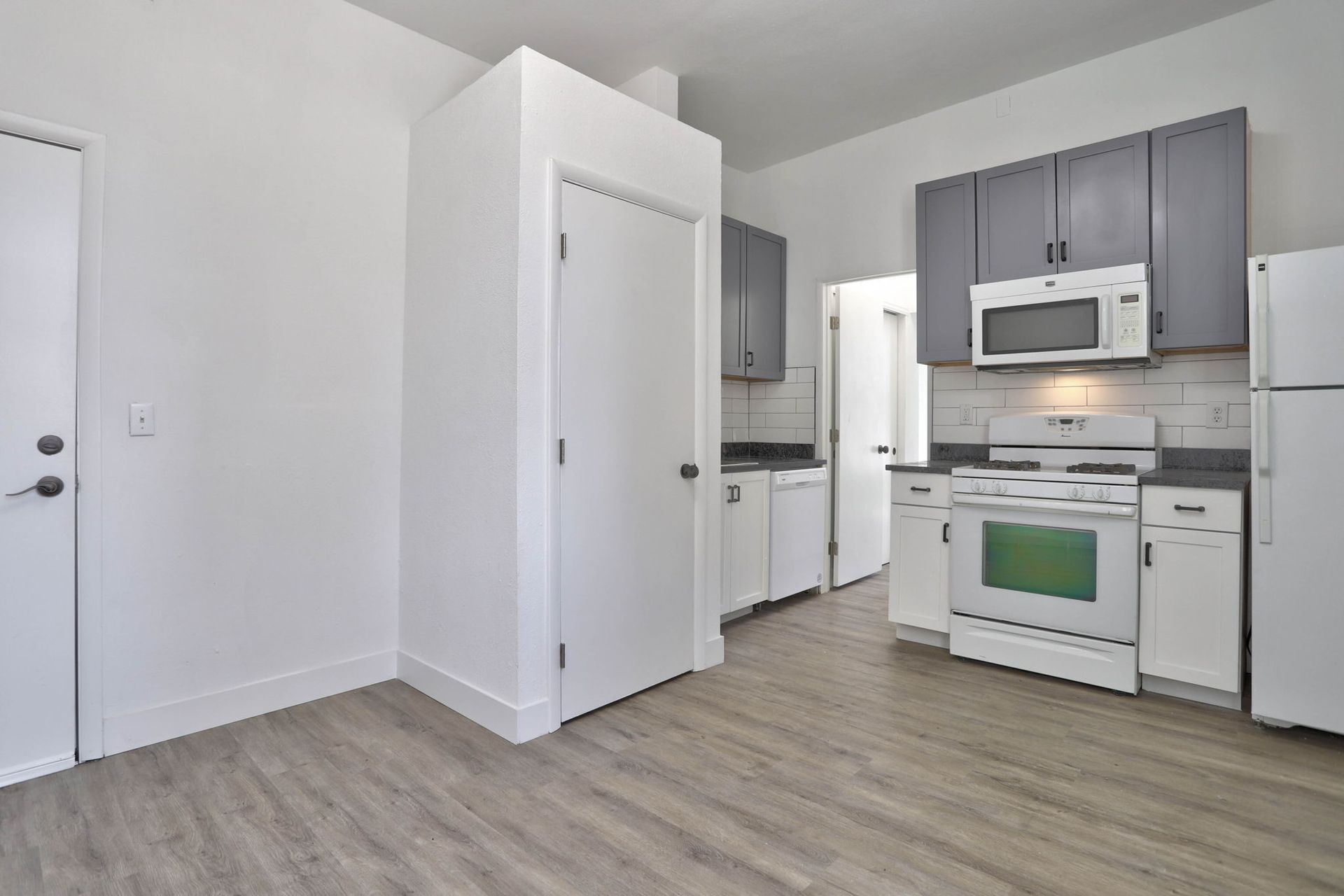a kitchen with a stove , refrigerator , microwave and cabinets .
