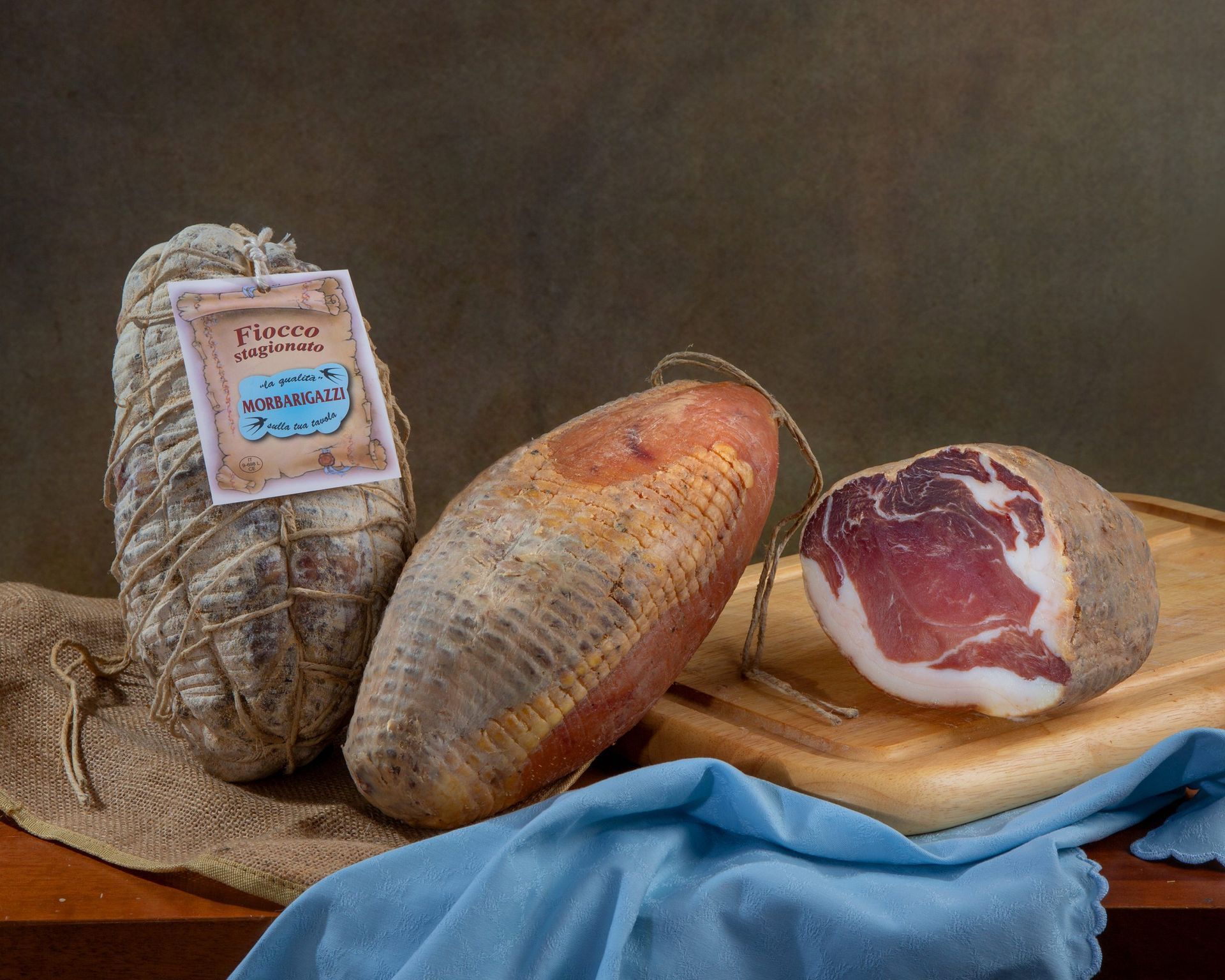 Due pezzi di prosciutto sono appoggiati su un tagliere di legno su un tavolo.