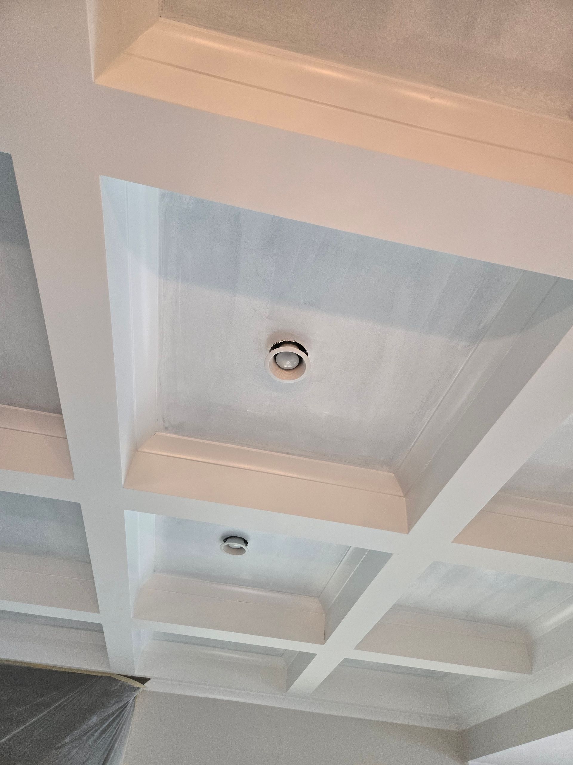 White coffered ceiling with recessed lighting.