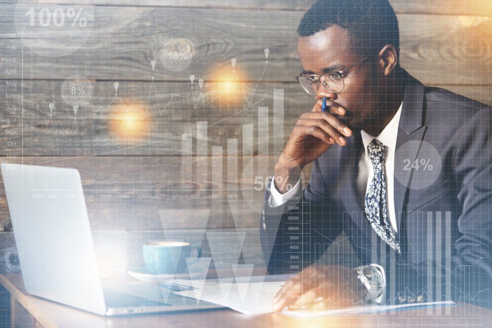 Un homme en costume et cravate est assis à un bureau avec un ordinateur portable.