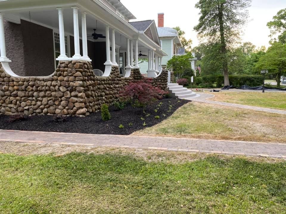 The front of a house with a stone wall and a porch.