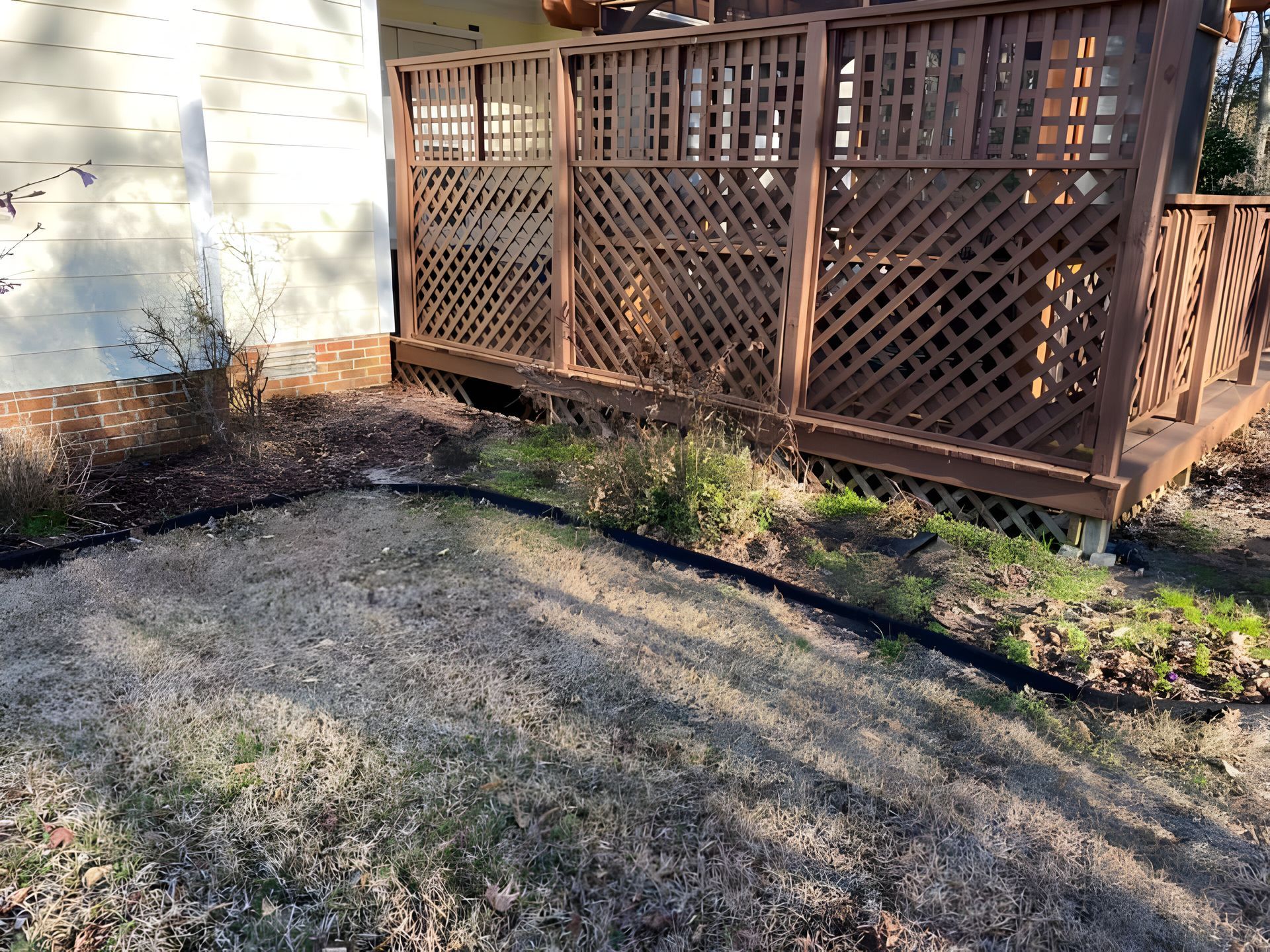 A house with a deck and a fence in front of it.