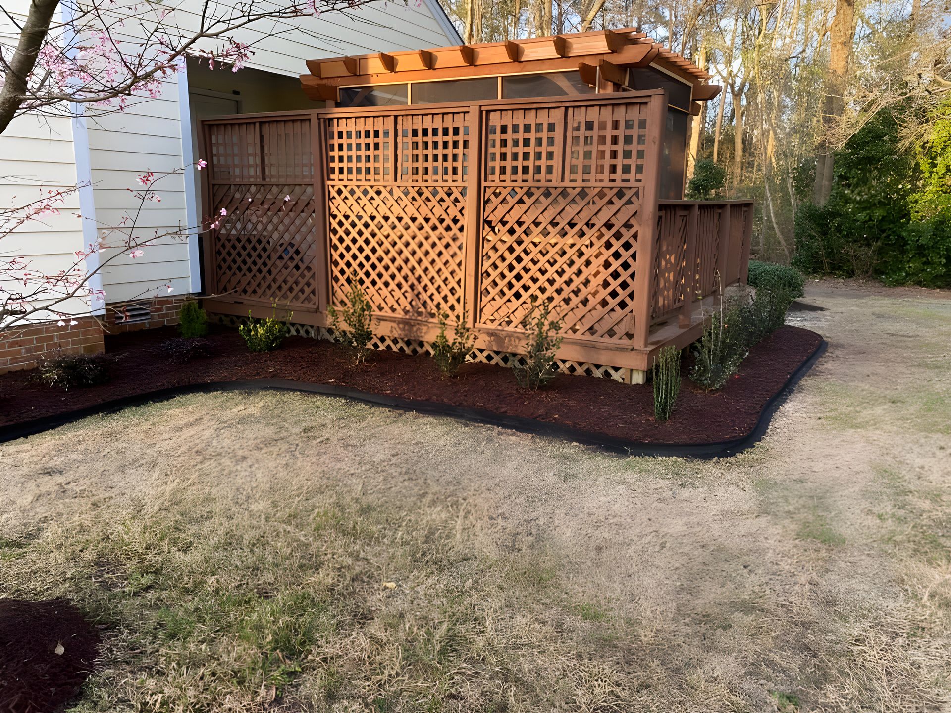 A wooden pergola is sitting in the backyard of a house.