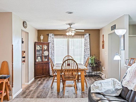A living room with a dining room table and chairs and a ceiling fan.