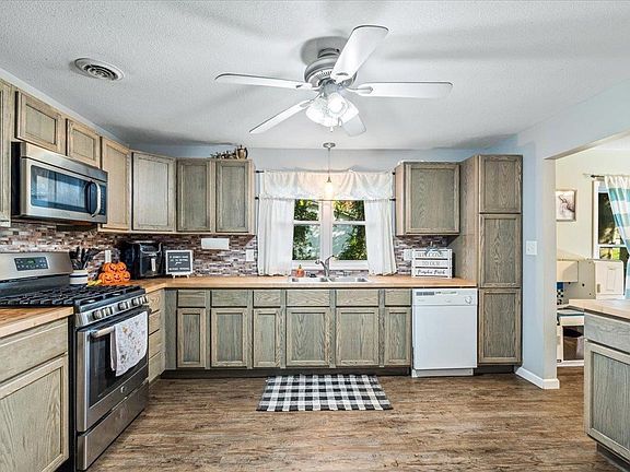 A kitchen with wooden cabinets , stainless steel appliances , and a ceiling fan.