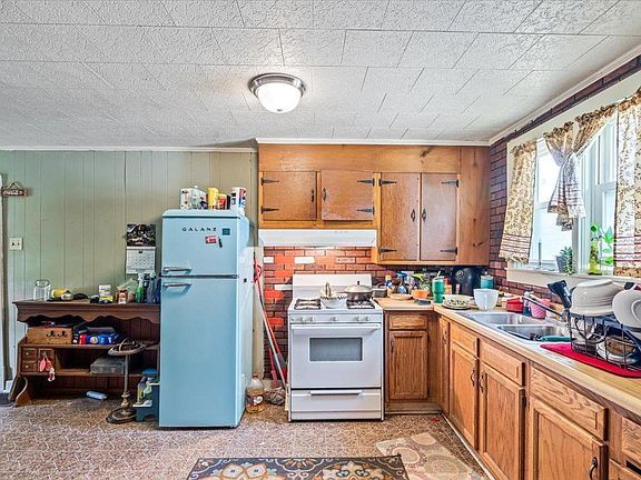 A kitchen with a blue refrigerator , stove , and sink.